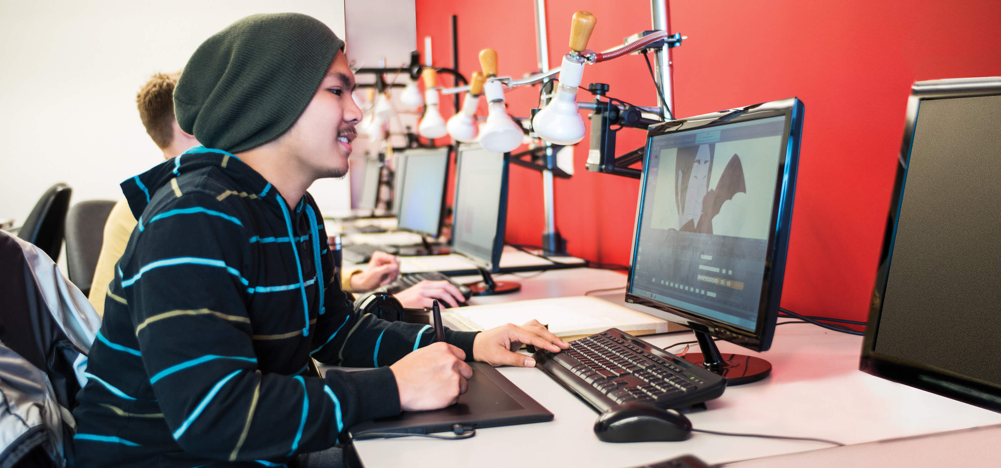 A DigiPen student works with a drawing tablet in front of a computer screen