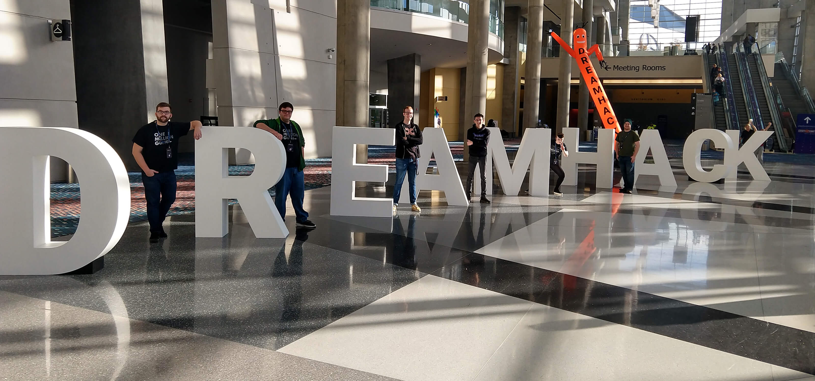 Six DigiPen students stand next to giant letters that spell out ‘DREAMHACK’