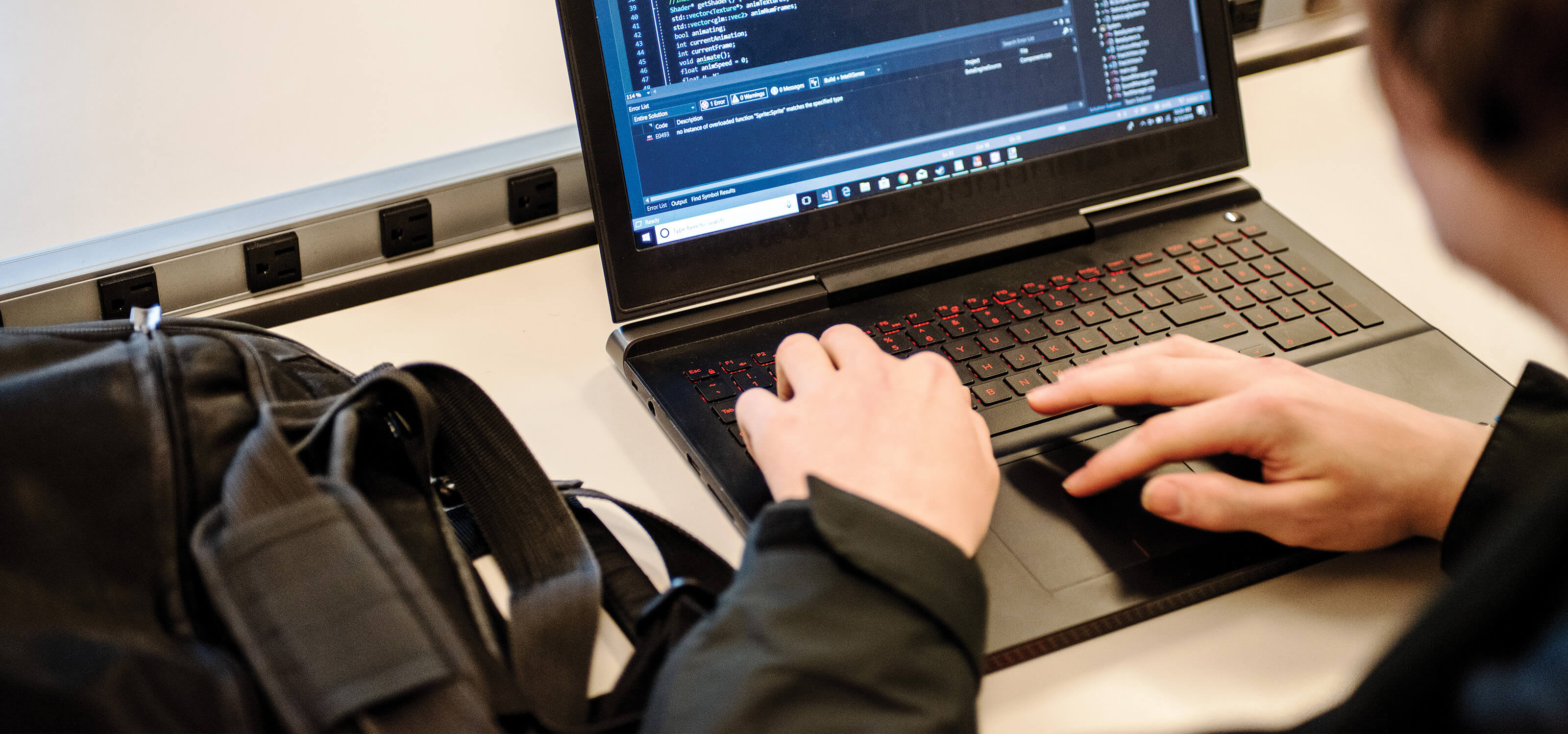 A student writes on code on their laptop computer.