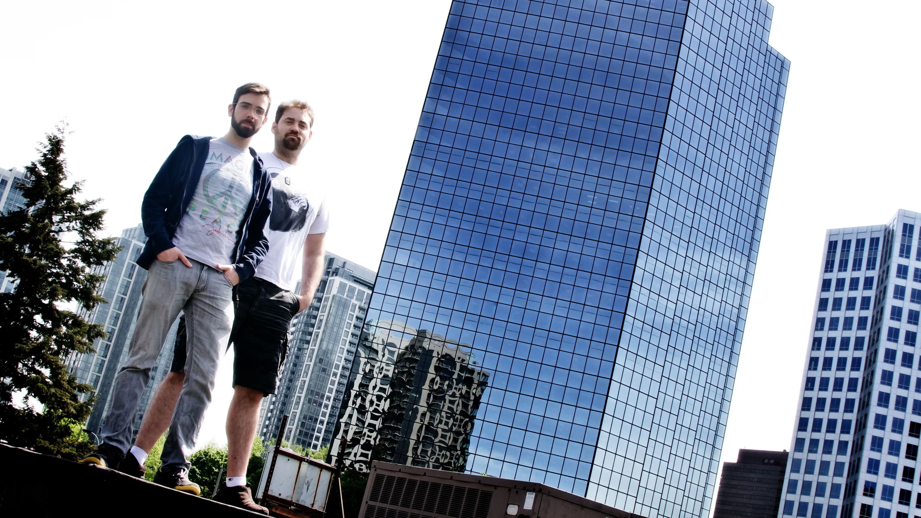 DigiPen alumni Greg Raab and Ryan Fedje standing outside the glass-walled building that houses the Camoflaj office