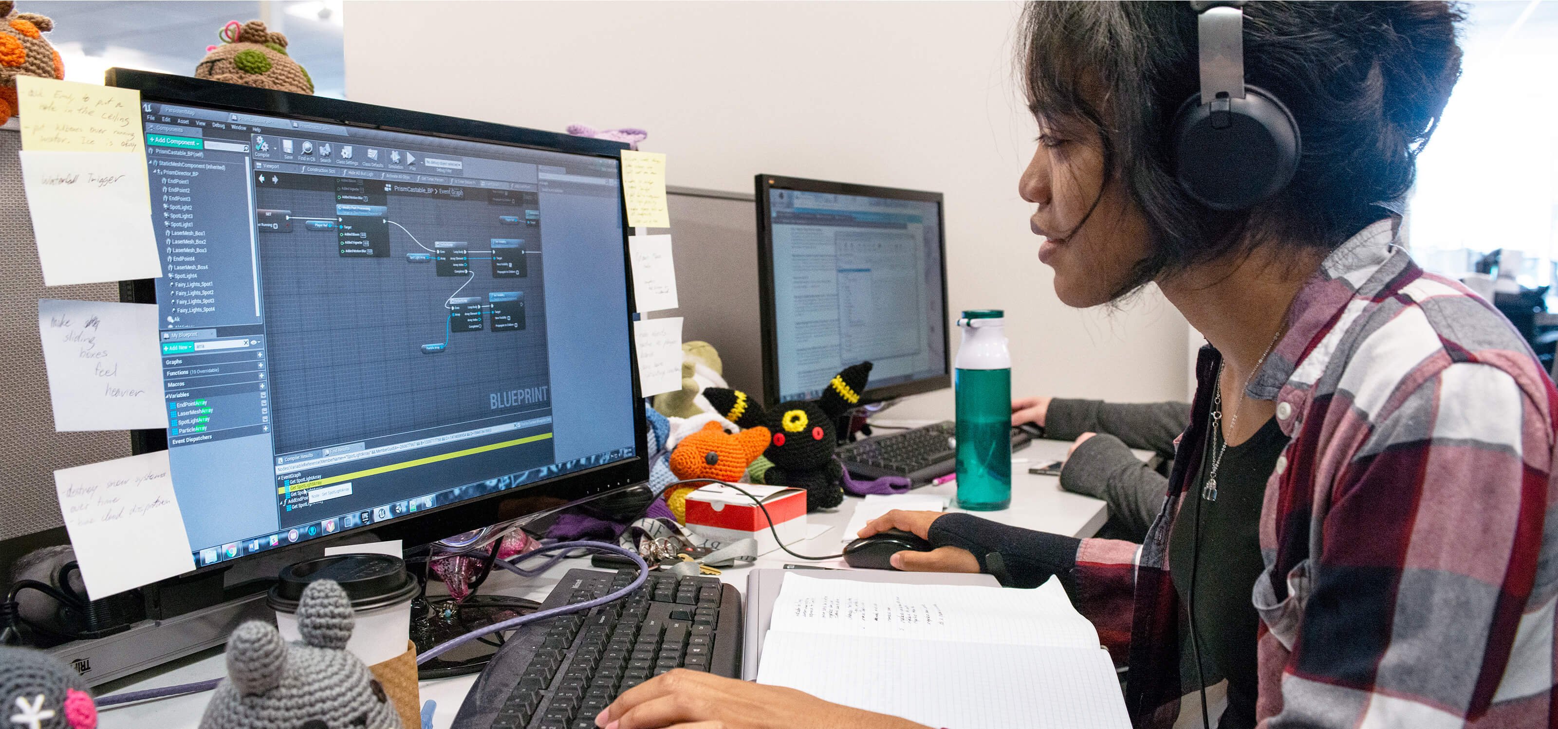 A DigiPen game design student works on her computer surrounded by knit plush toys.