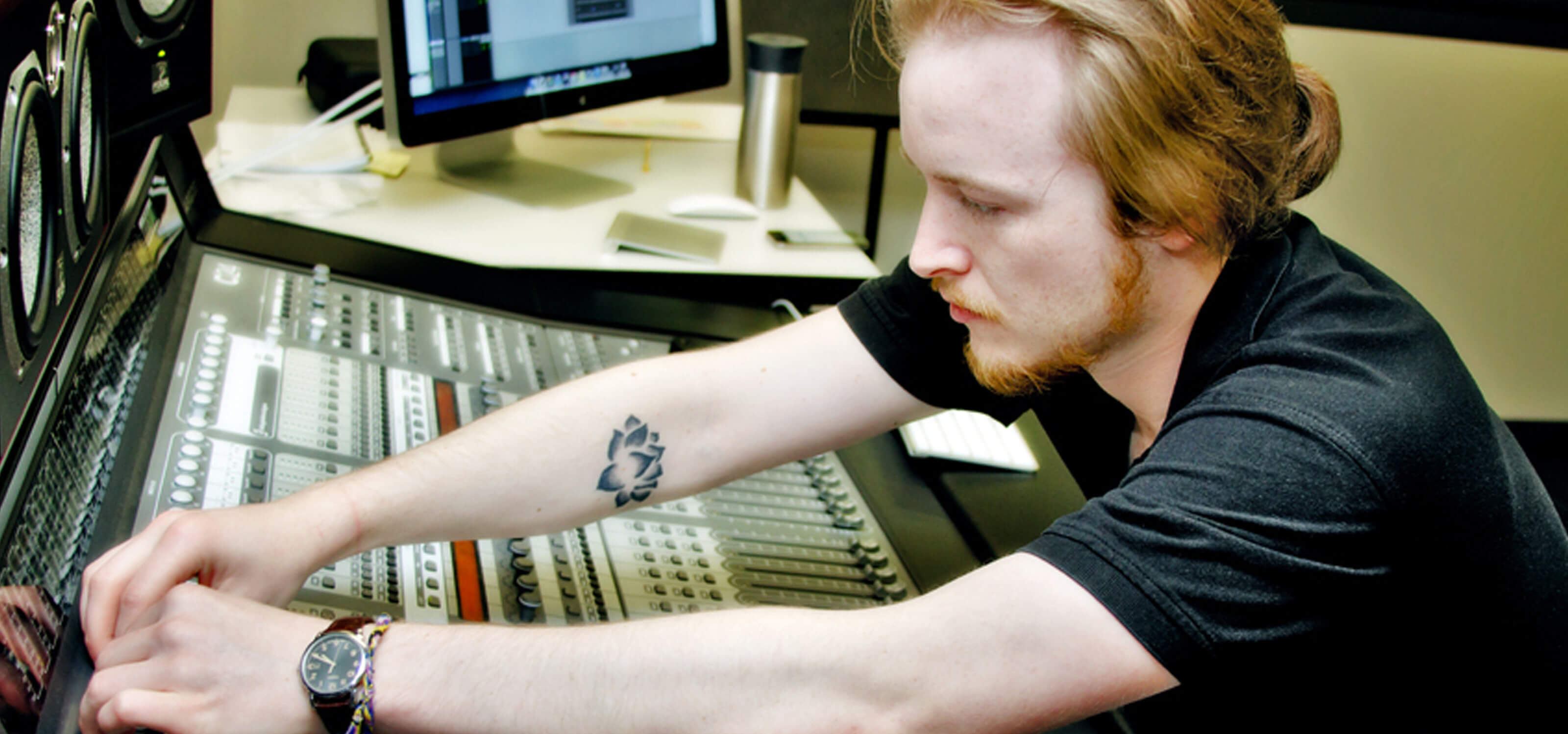 DigiPen student Ian Shores adjusting knobs on a sound board in a DigiPen recording studio