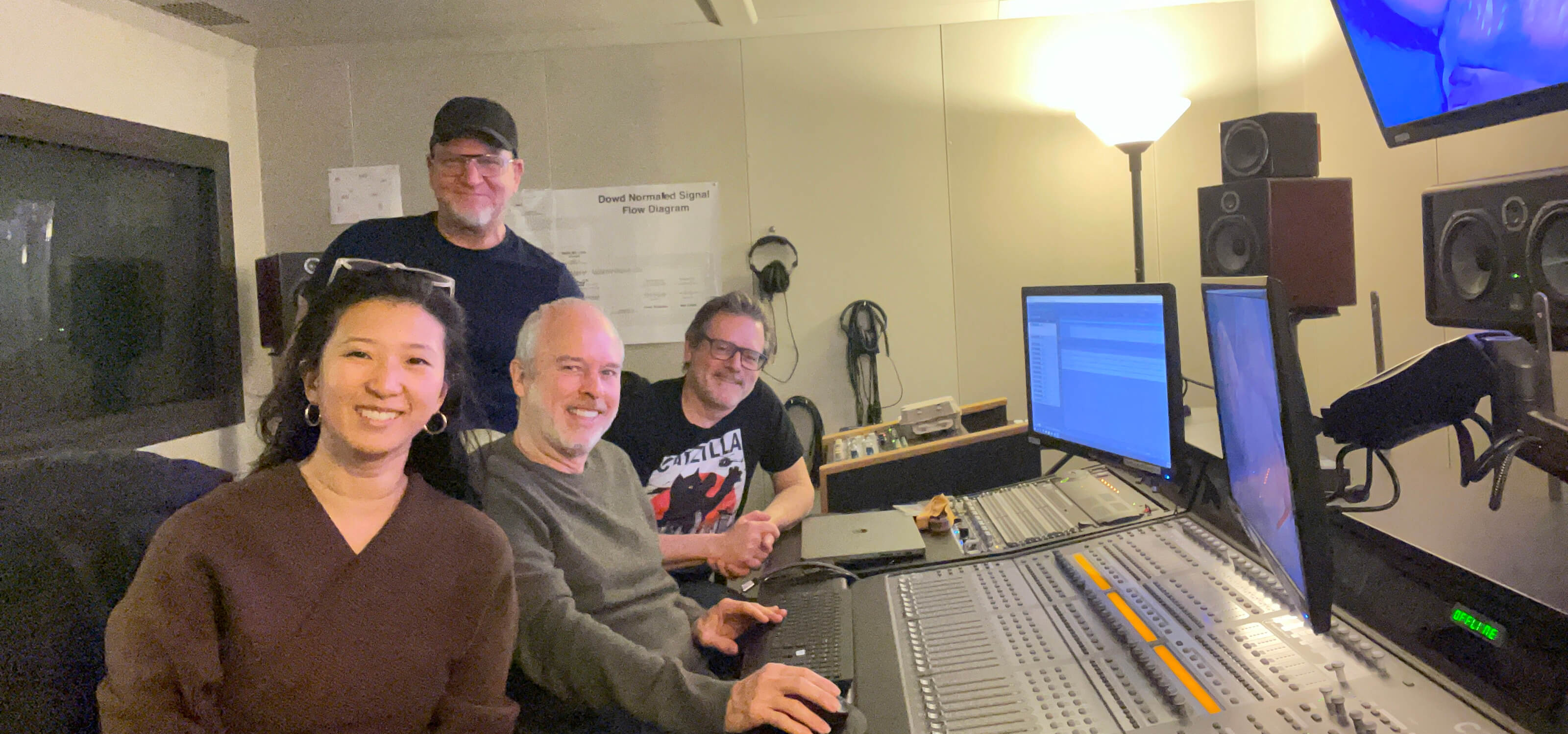 Clare Chun, Jazno Francoeur, Lawrence Schwedler, and Chris Mosio smile at camera while working in a sound production room.