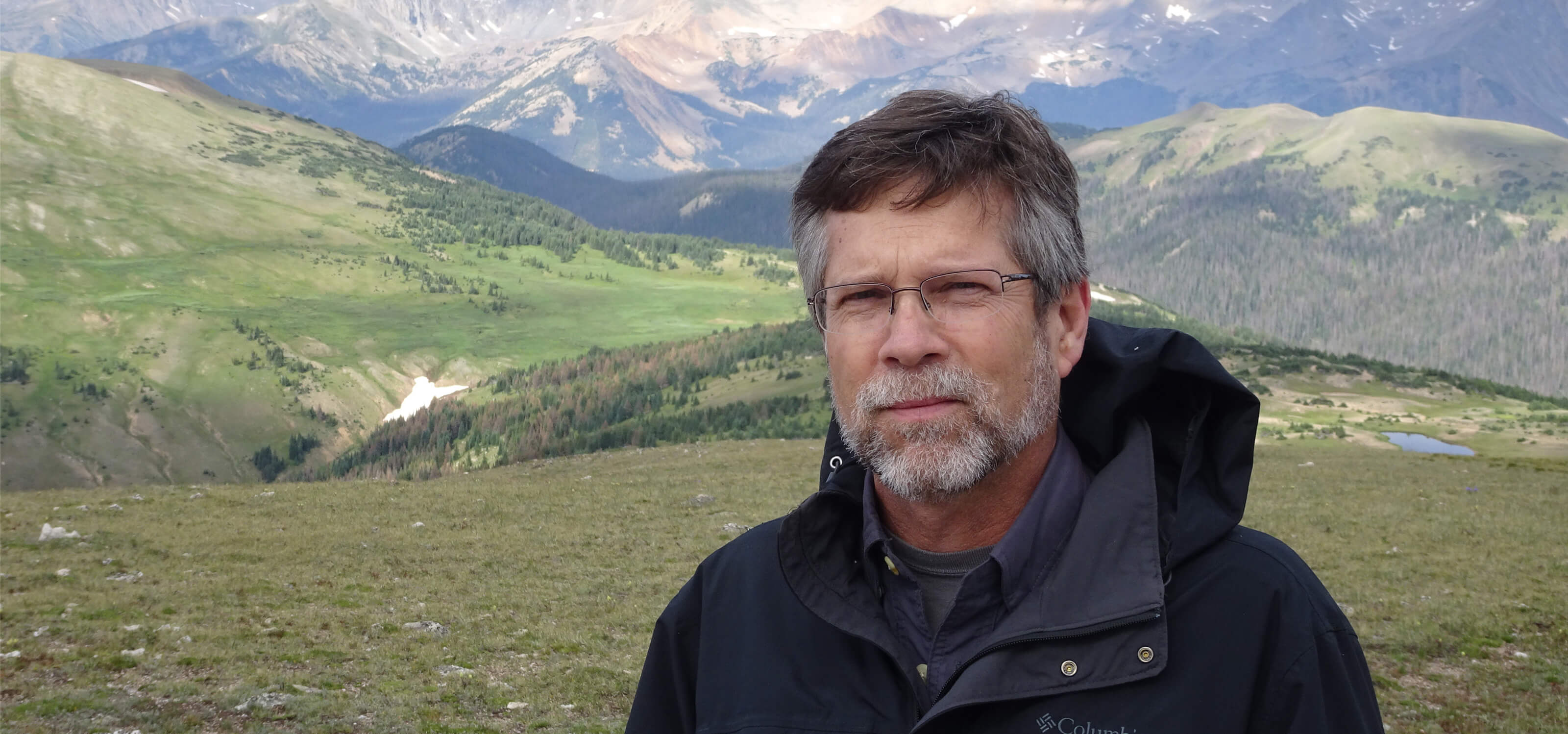 Professor James Peet stands in front of a vast valley and mountain range.