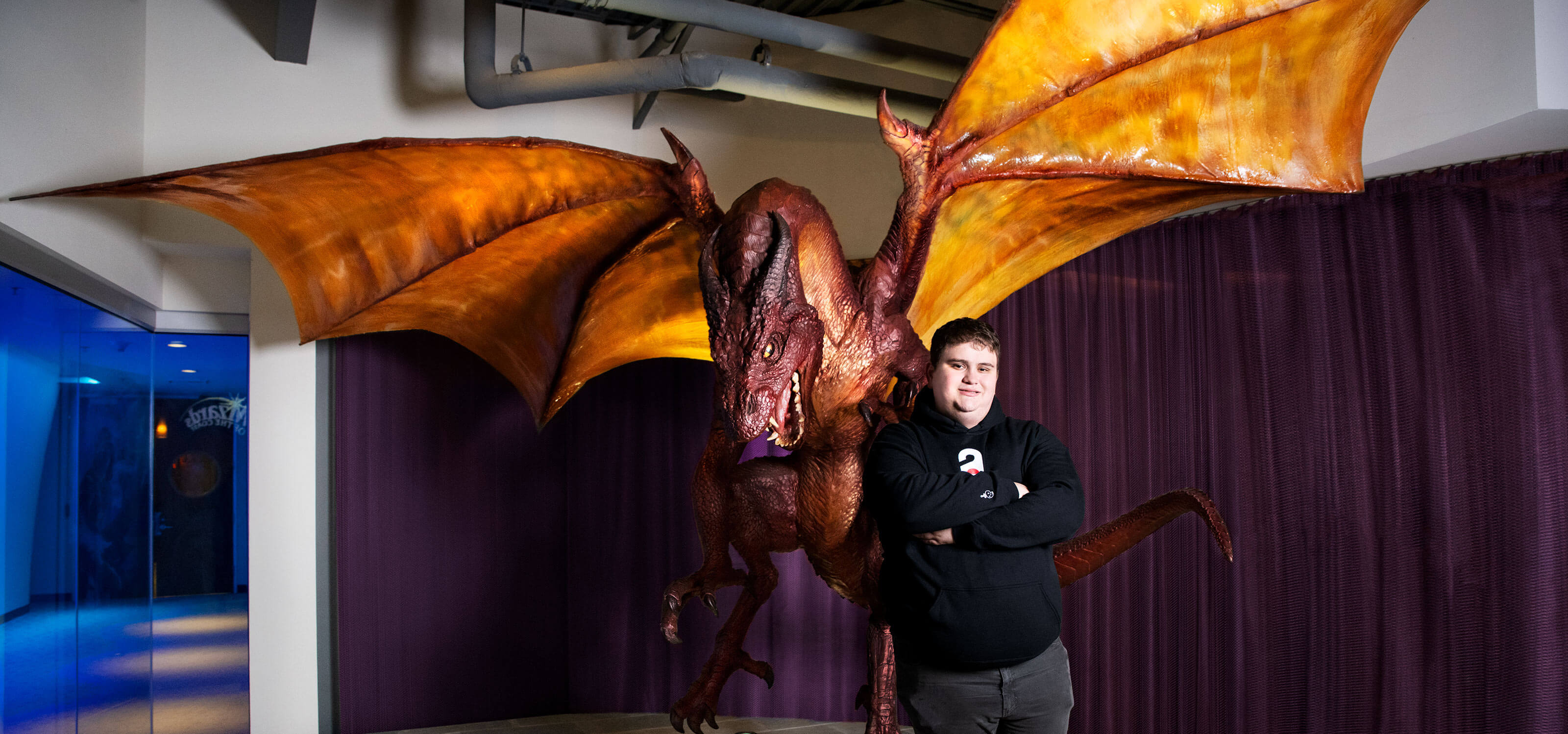 Kaan Palaz stands in front of a giant dragon statue at Wizards of the Coast headquarters.