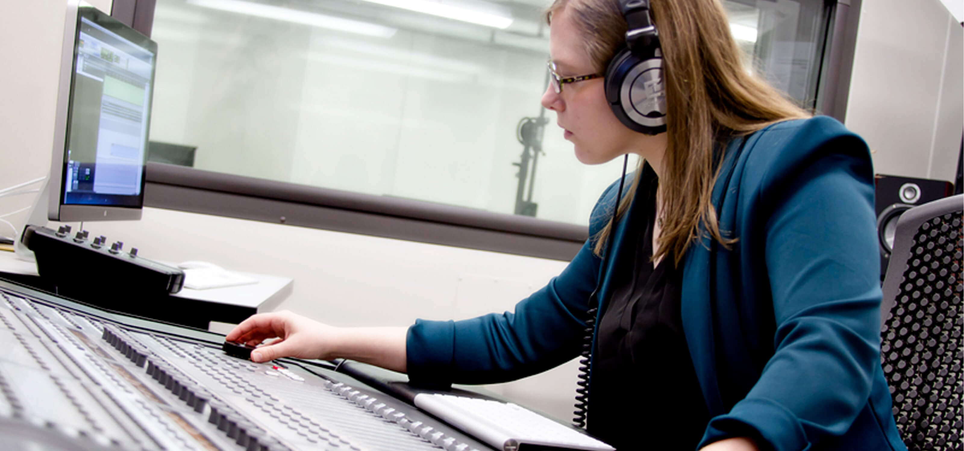 DigiPen student Kori Loomis adjusting knobs on a sound board in a DigiPen recording studio