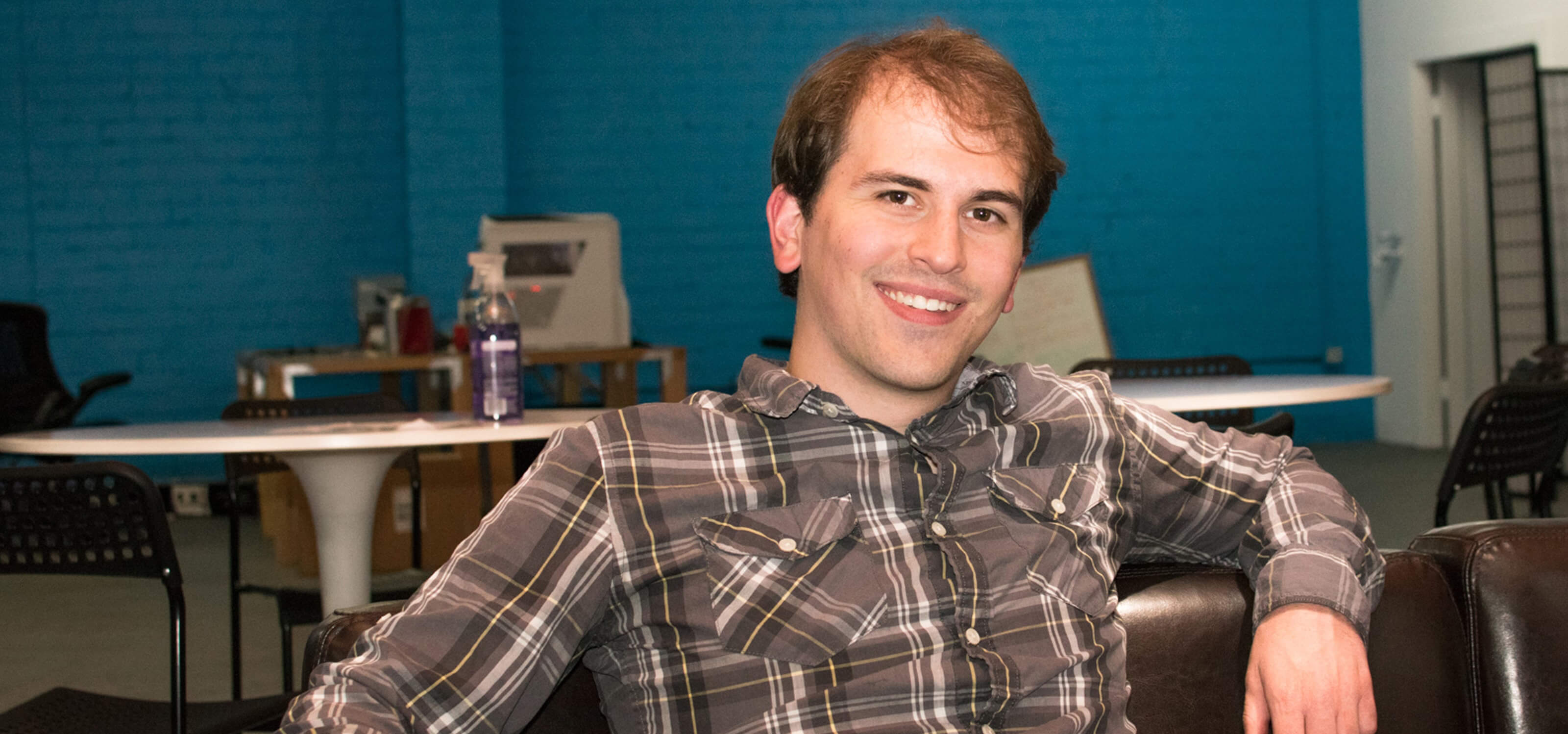 DigiPen alumnus Logan Fieth smiling while sitting on a couch