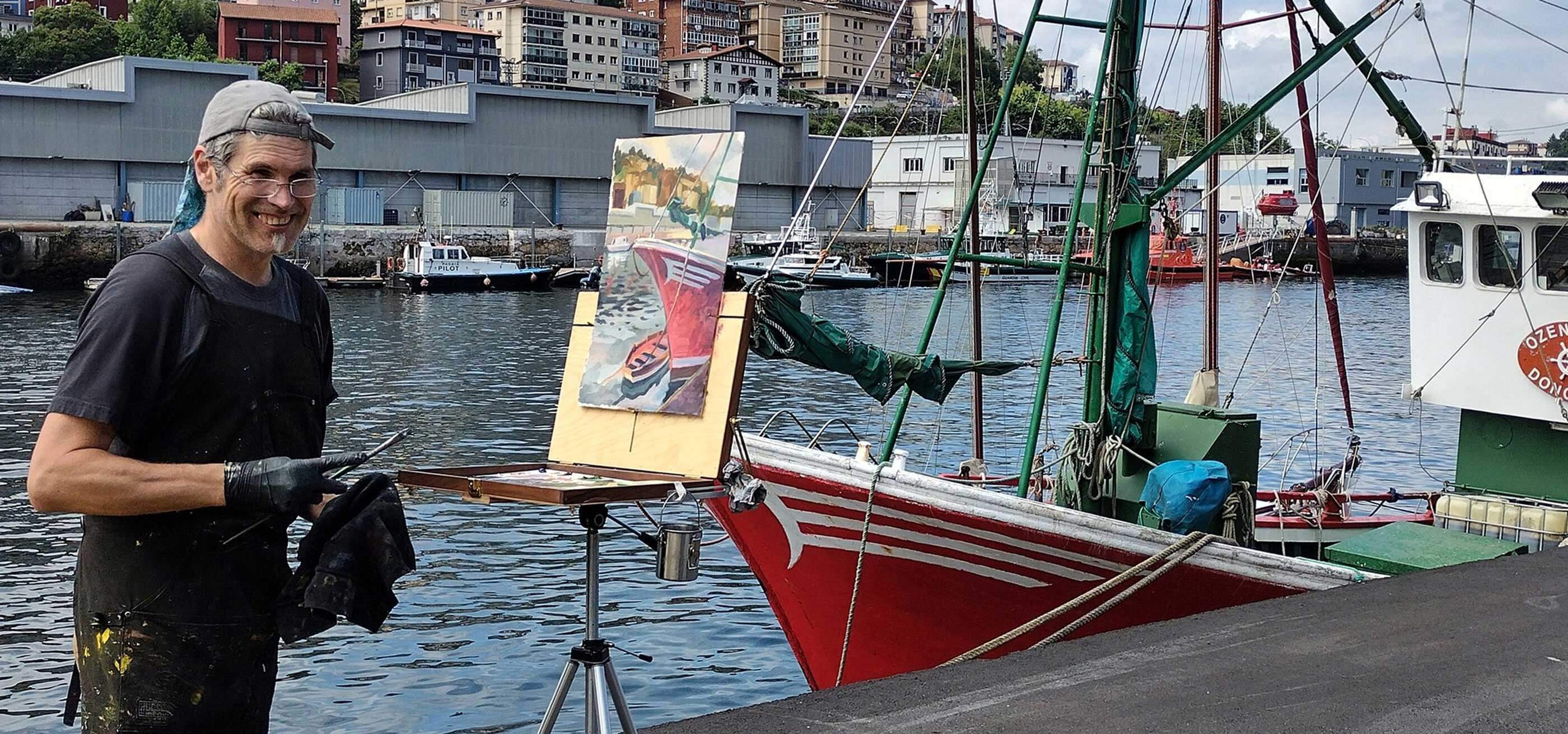 Steffon Moody stands and smiles as he paints the surrounding harbor and boat onto his canvas