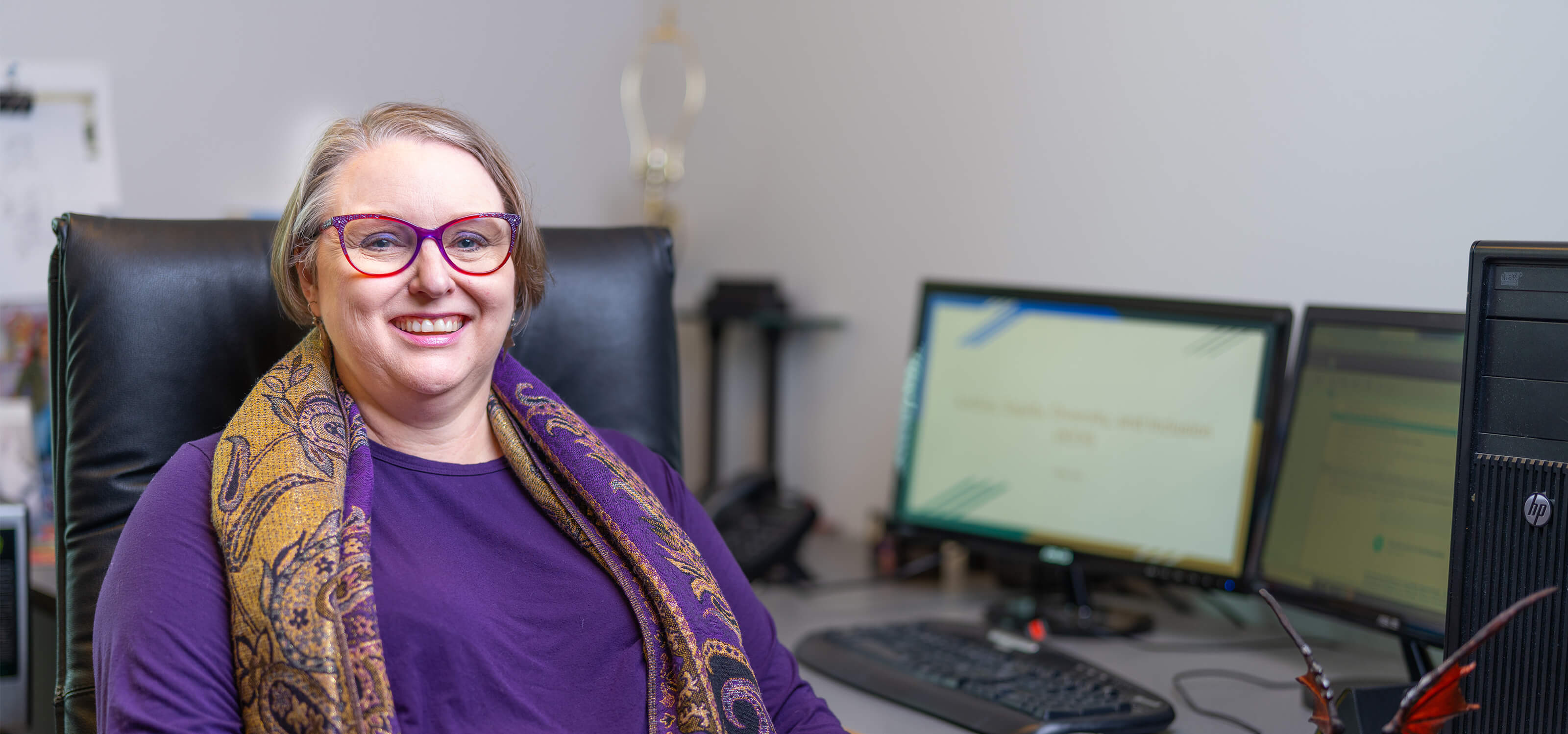 DigiPen senior lecturer Sonia Michaels sits at her desk near a dragon figurine. 