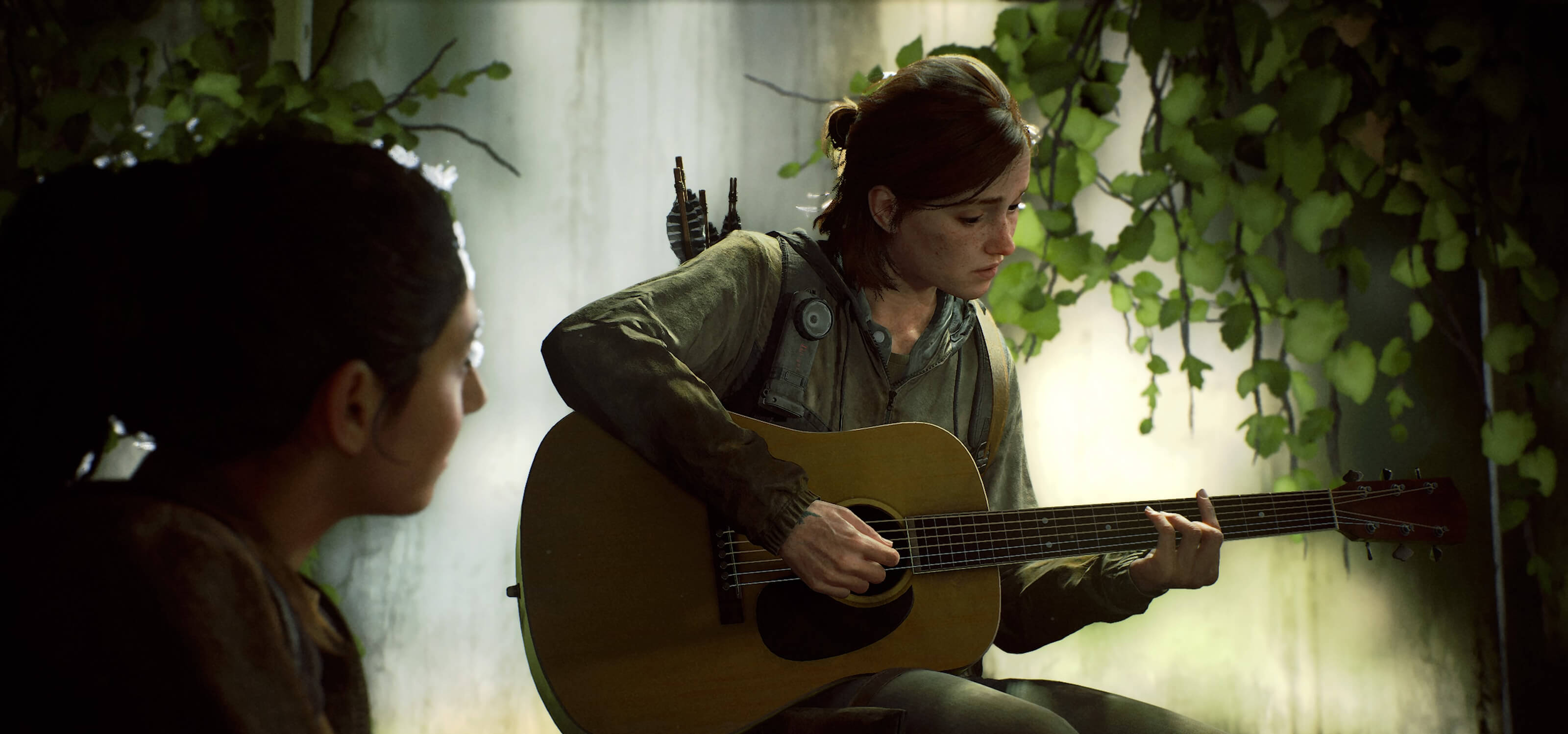 Ellie plays guitar as another woman watches