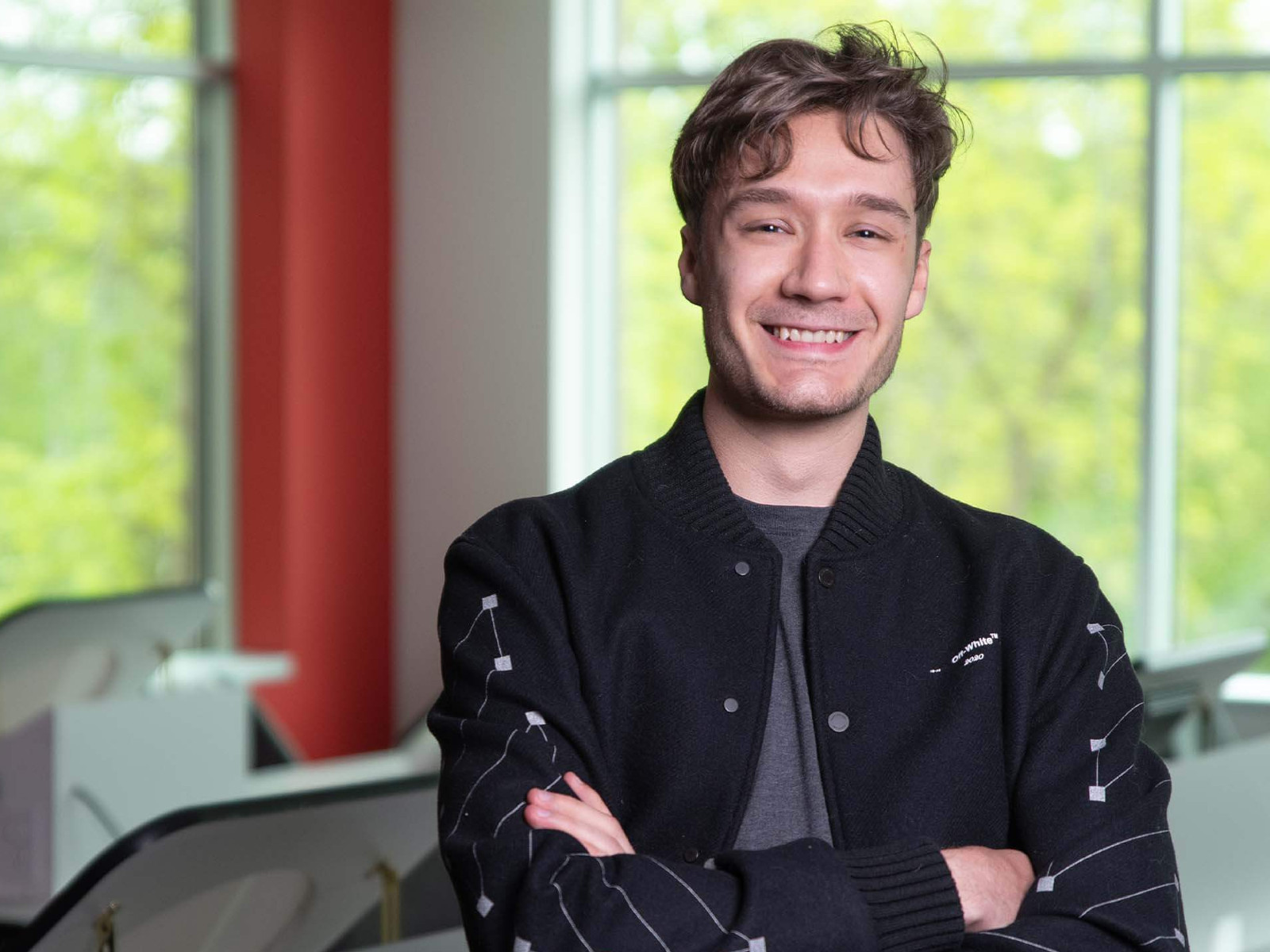 Christophe Bouchard in lecture hall standing with arms crossed wearing a black jacket