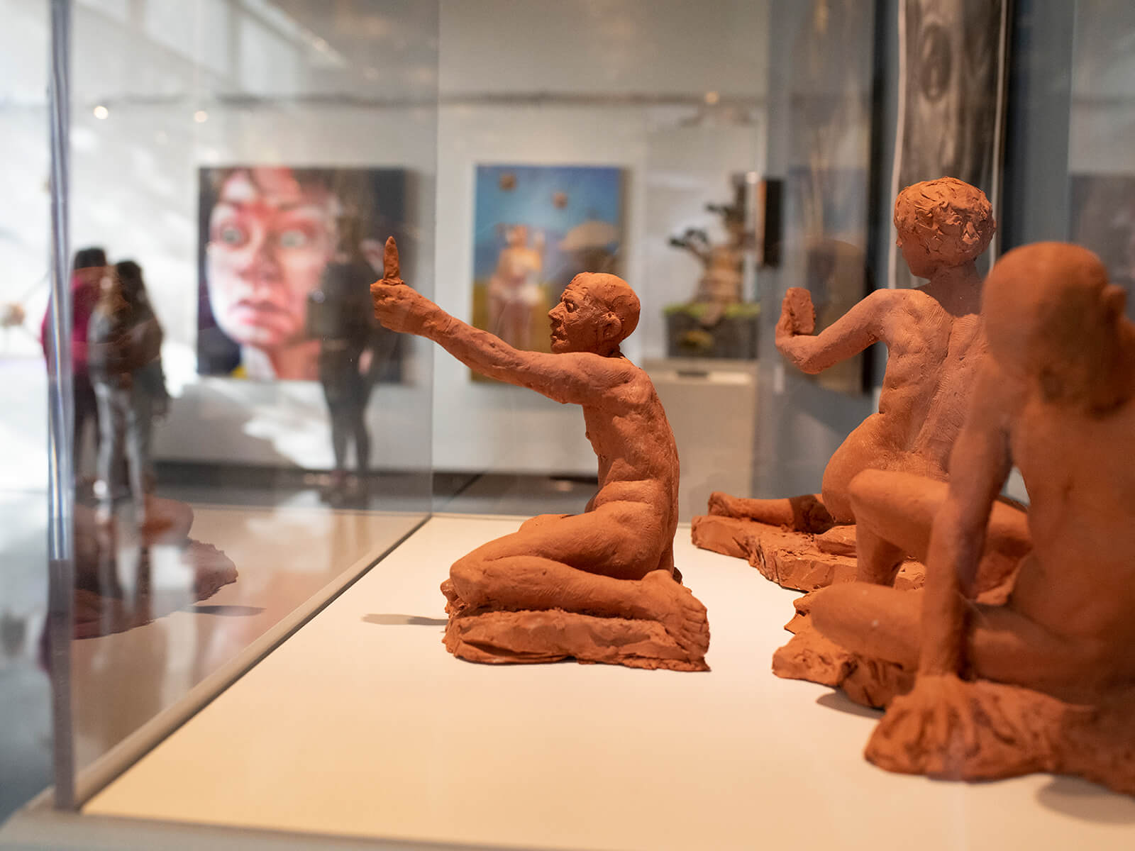 Three terracotta figure sculptures by Alecia Rossano on display at the Bellevue Art Museum.