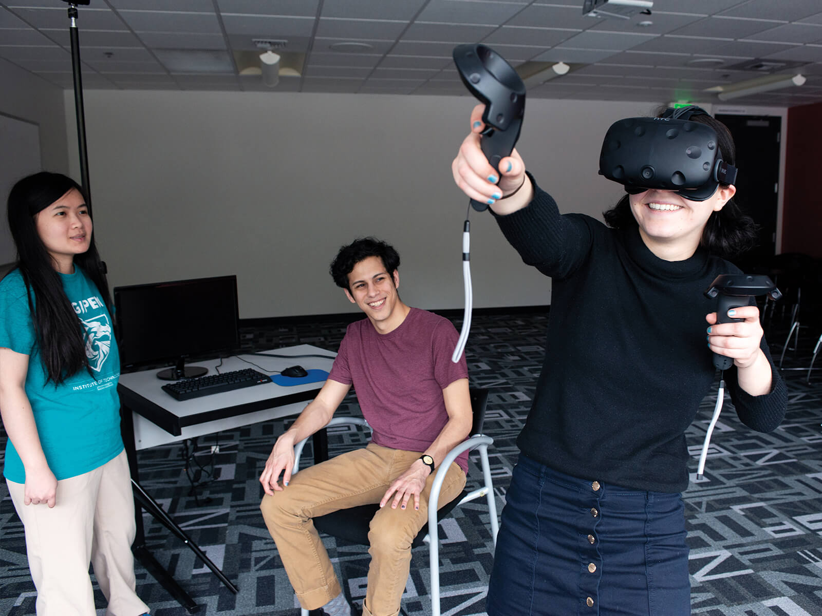 A DigiPen student tries out their VR game team project as their teammates smile at them.
