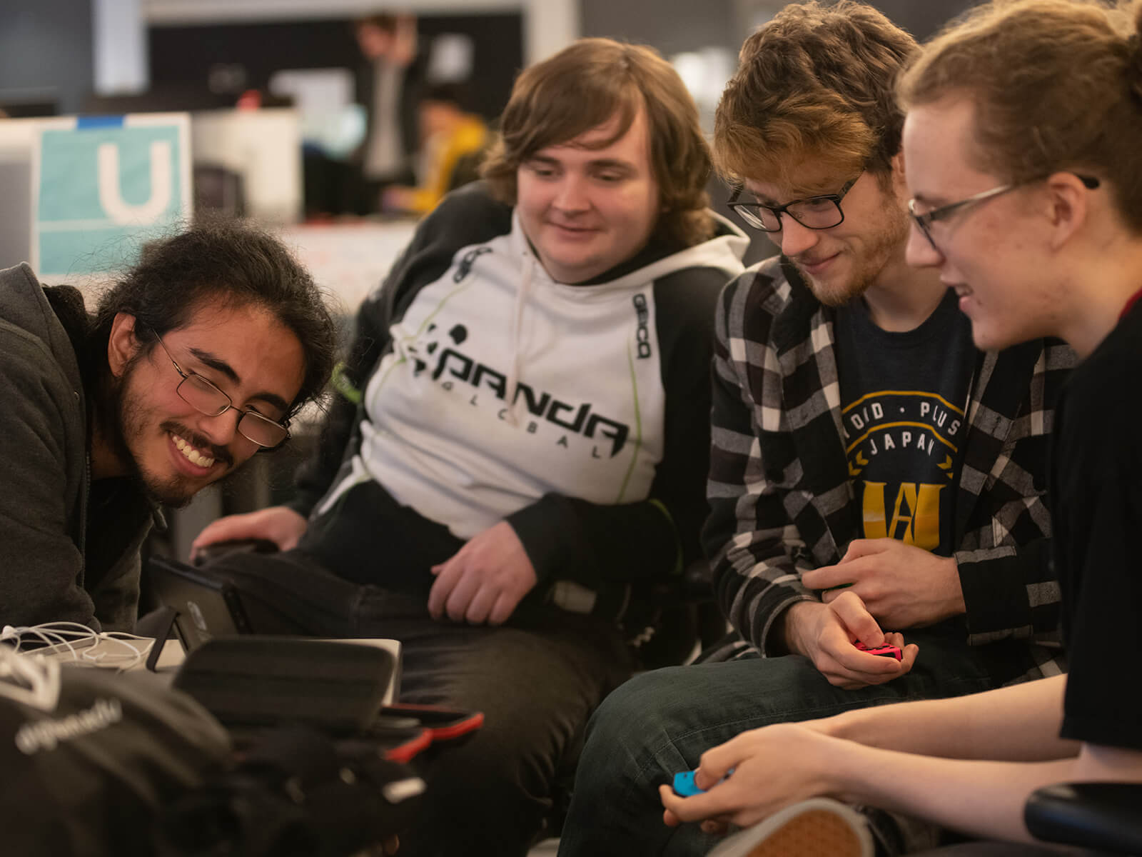 	Four DigiPen game teammates smile as they look at their project on screen.