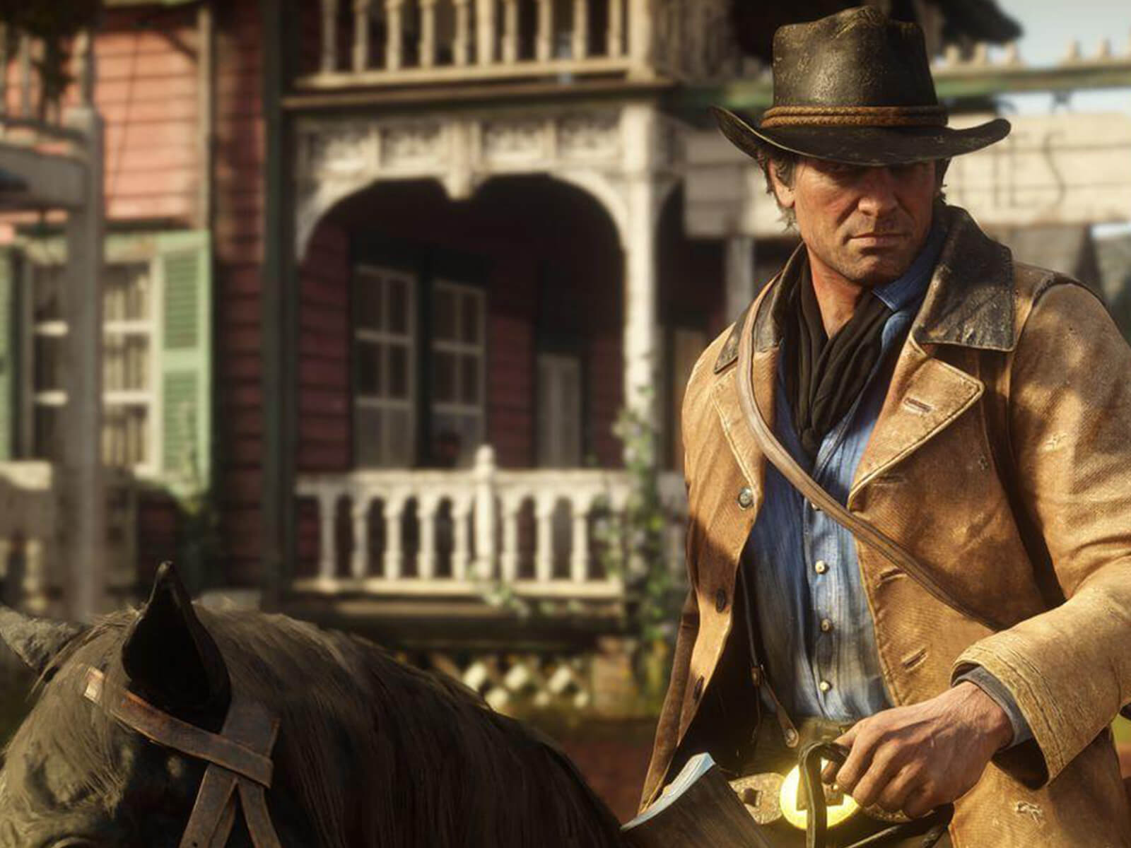 Red Dead Redemption 2’s protagonist Arthur Morgan rides into town on his horse.