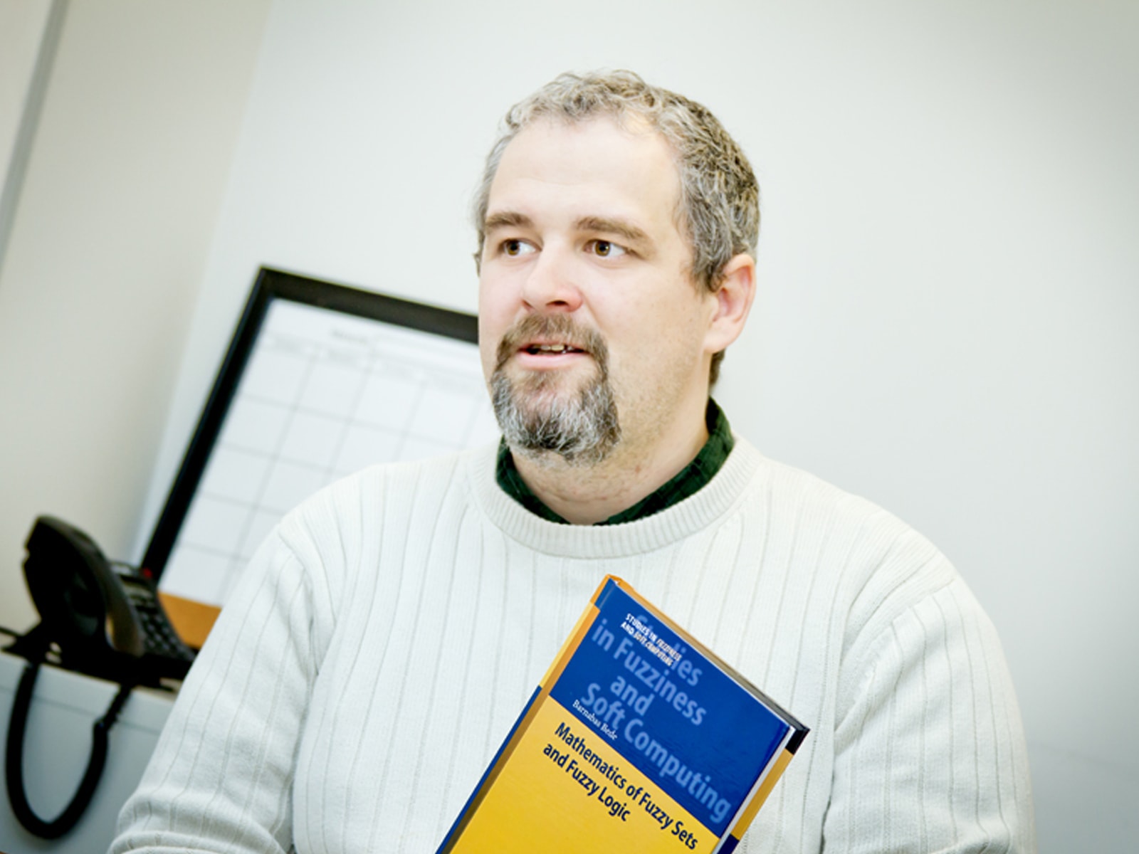 DigiPen mathematics professor Dr. Barnabas Bede holding a copy of his book, Mathematics of Fuzzy Sets and Fuzzy Logic