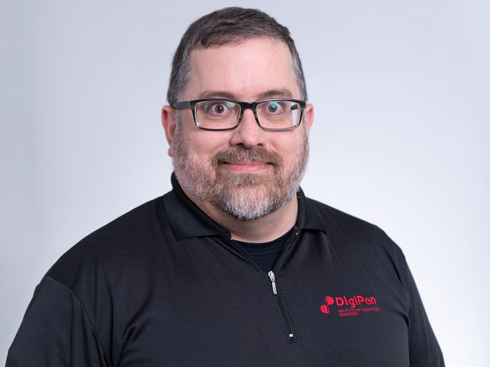 Program director Benjamin Ellinger smiles for the camera in a DigiPen polo shirt.