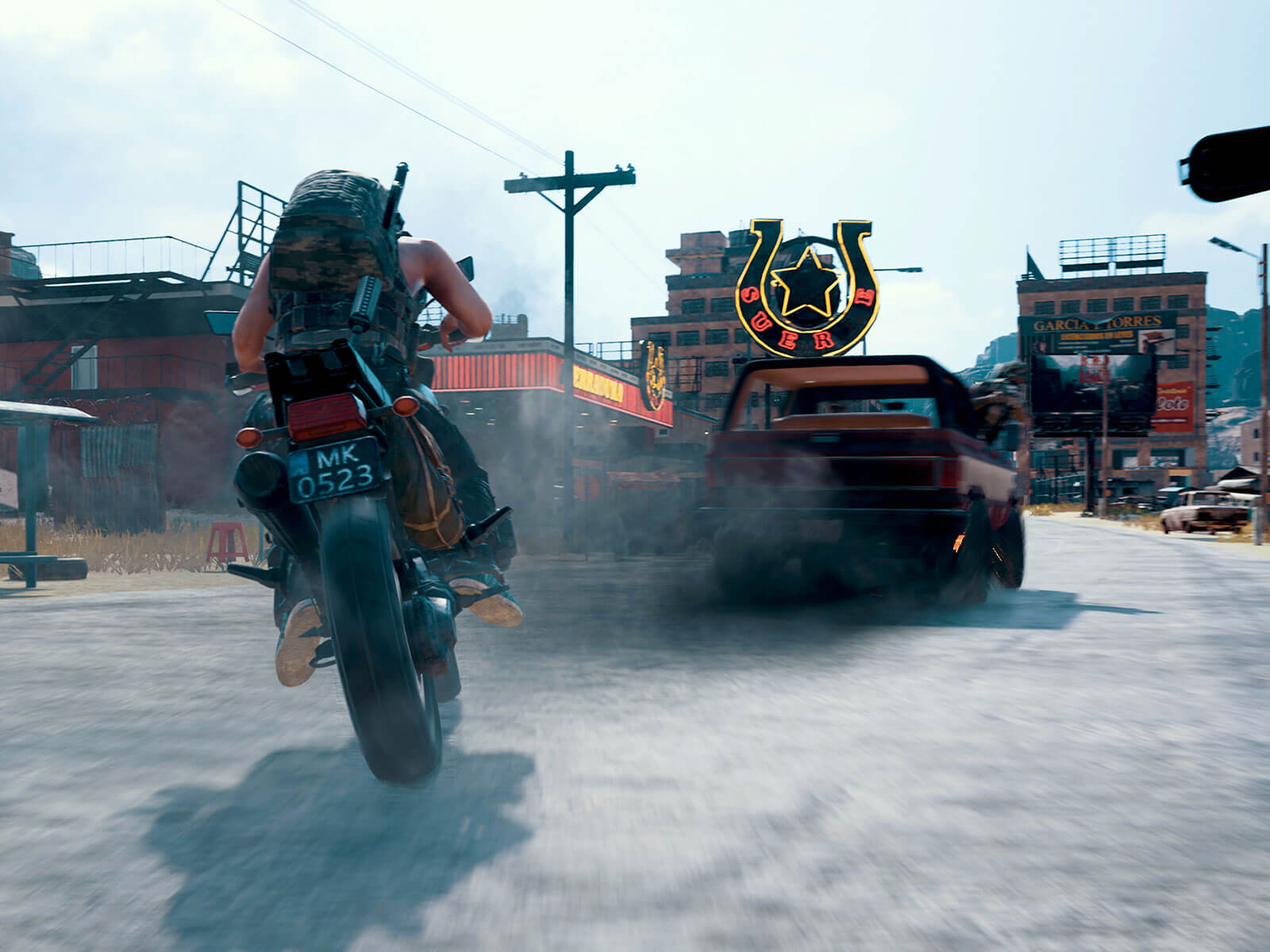 A player on a motorcycle chases a smoking truck down a western themed street