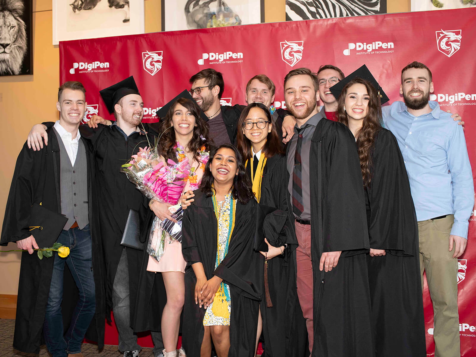 A group of DigiPen grads pose in front of a red backdrop
