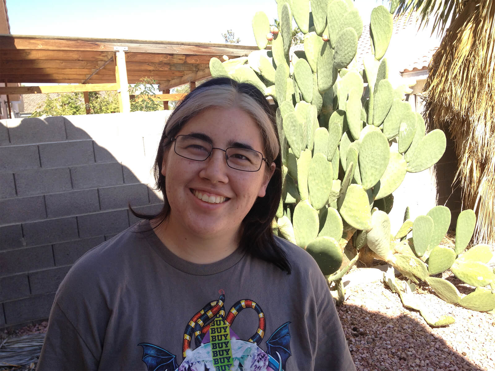 DigiPen graduate and Spry Fox senior software engineer Molly Jameson poses in front of a cactus. 