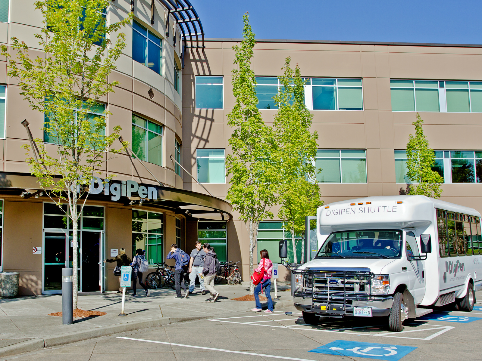 Students getting off the DigiPen shuttle bus in front of the DigiPen building