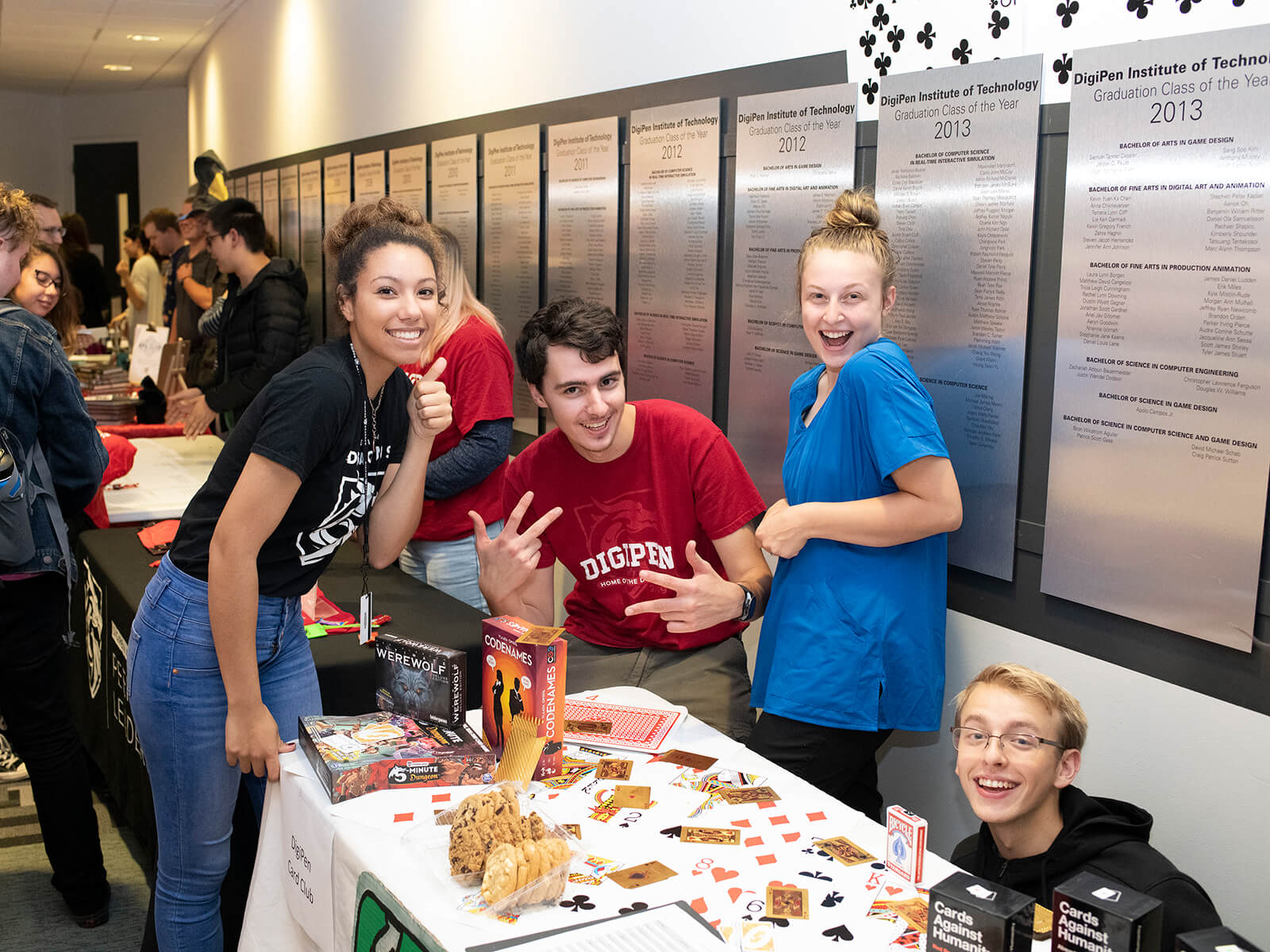 Students smile and pose around a table of board games.