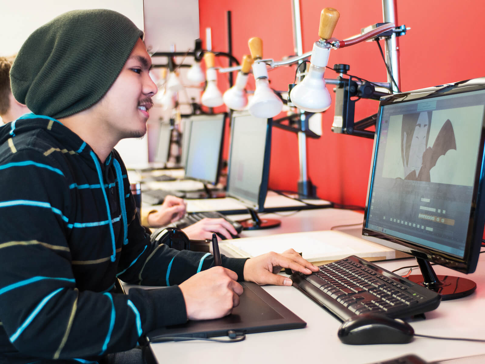 A DigiPen student works with a drawing tablet in front of a computer screen