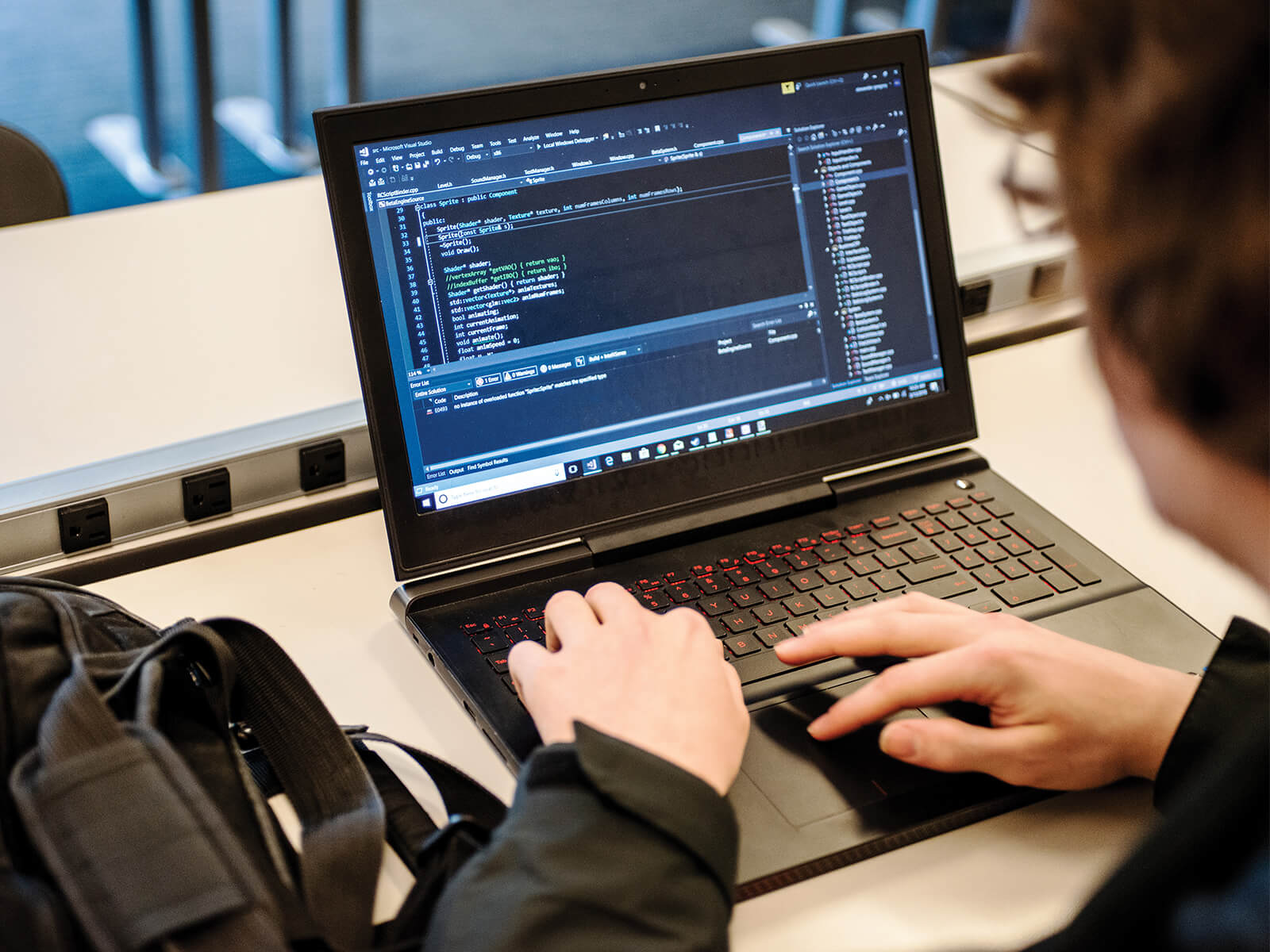 A student writes on code on their laptop computer.