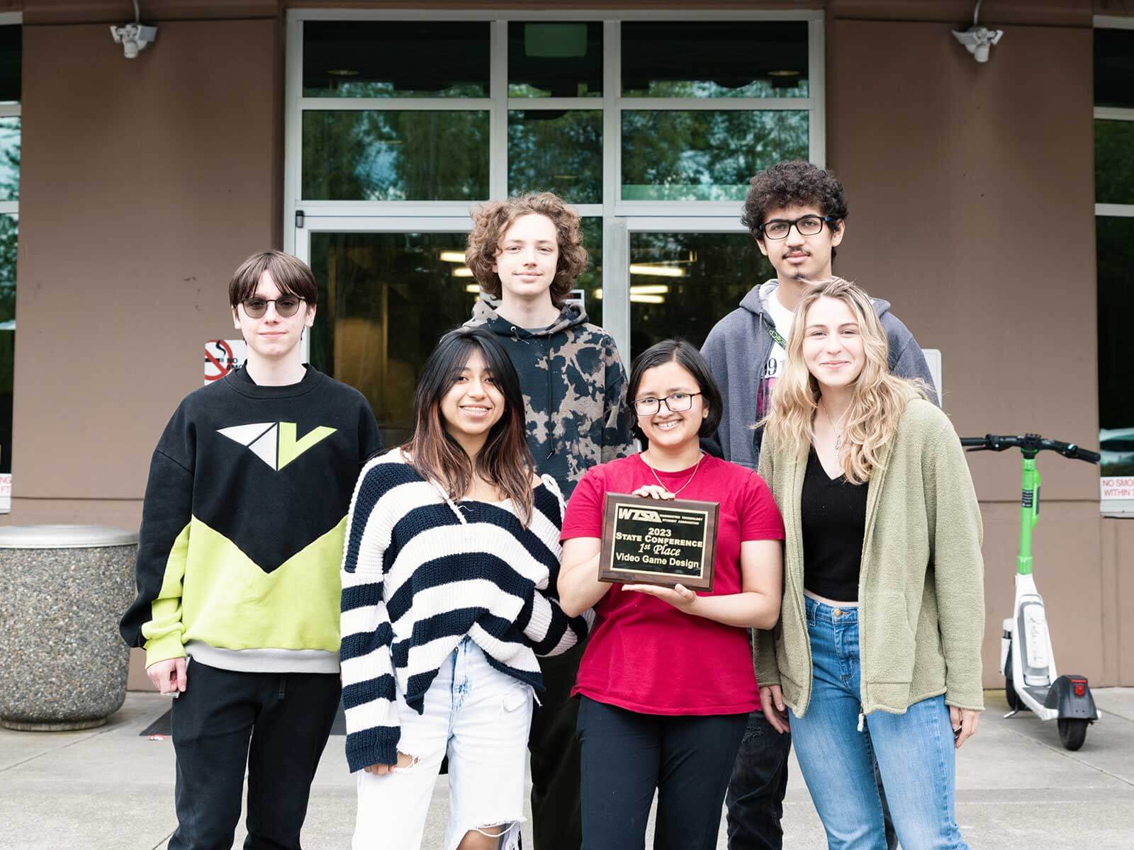 Group photo of six DigiPen WANIC students posing with first-place award plaque