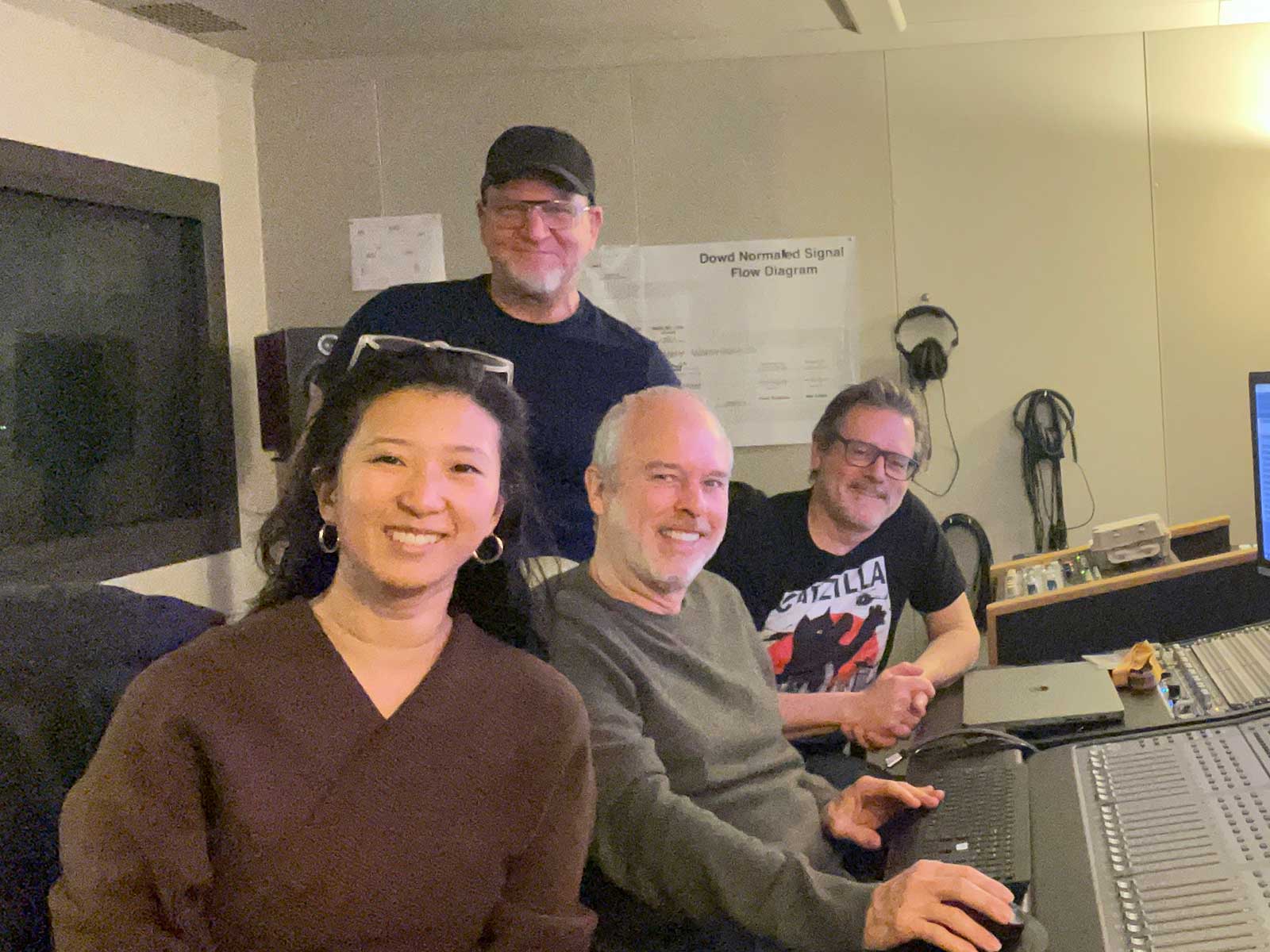 Clare Chun, Jazno Francoeur, Lawrence Schwedler, and Chris Mosio smile at camera while working in a sound production room.