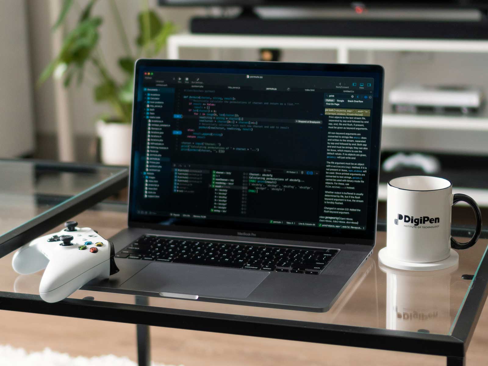 A laptop sits between an Xbox controller and a DigiPen branded mug.