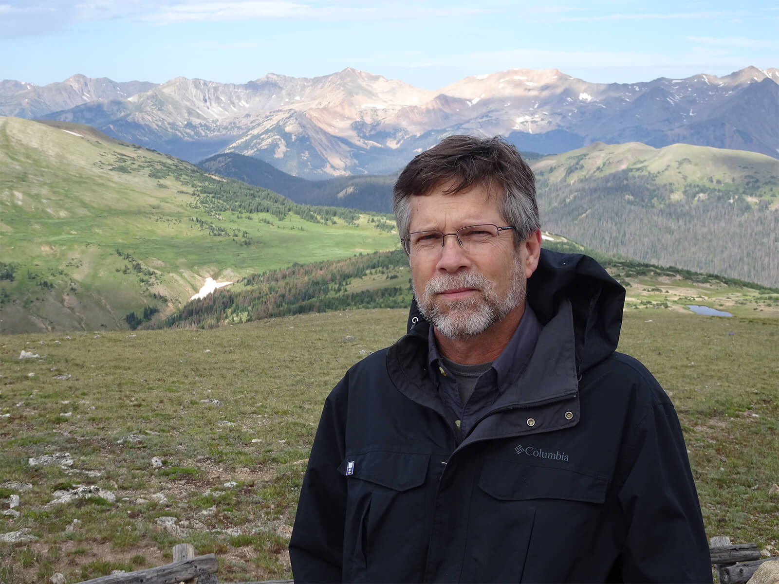 Professor James Peet stands in front of a vast valley and mountain range.