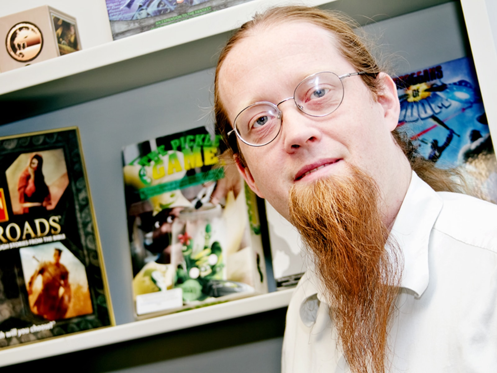 DigiPen game design lecturer Jeremy Holcomb in front of a bookshelf filled with games in his office