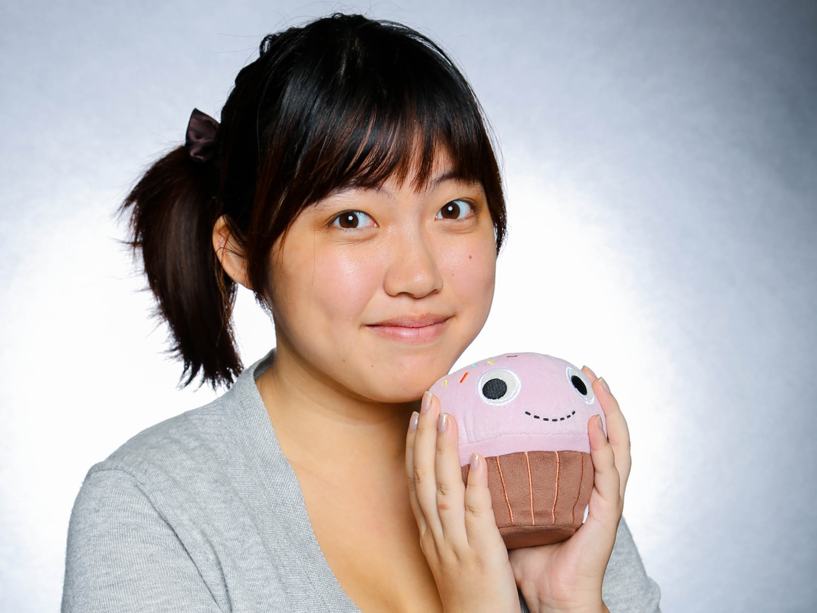 DigiPen alumna Jessica Nam posing with a cupcake-shaped plush toy