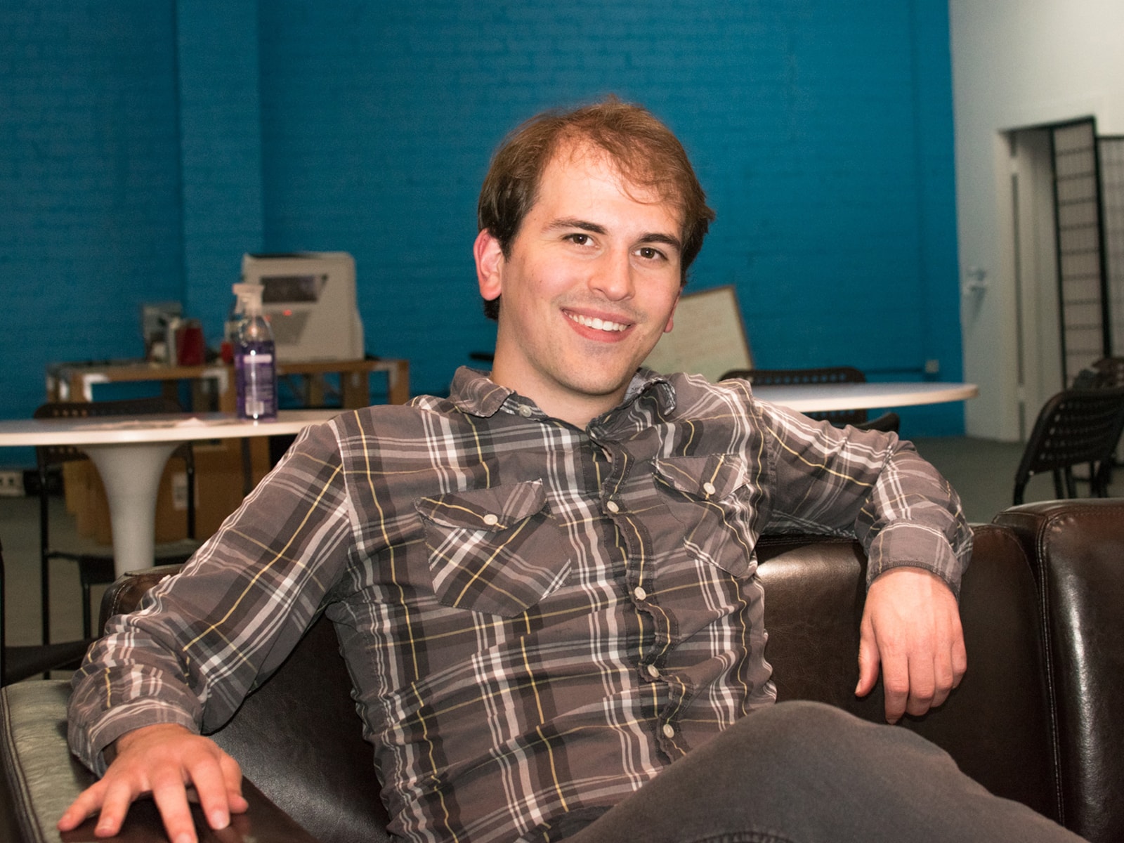 DigiPen alumnus Logan Fieth smiling while sitting on a couch