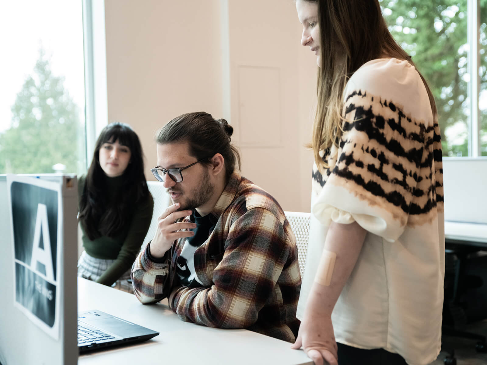 Mike Doeren looks at his laptop in DigiPen’s campus lab, surrounded by two other students.