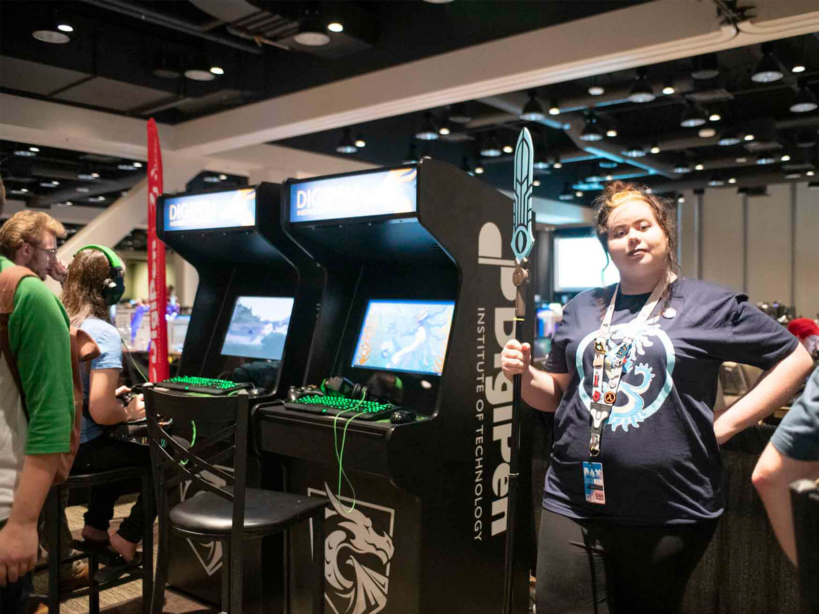 A DigiPen student staffs the PAX DigiPen arcade, cosplay spear in hand.