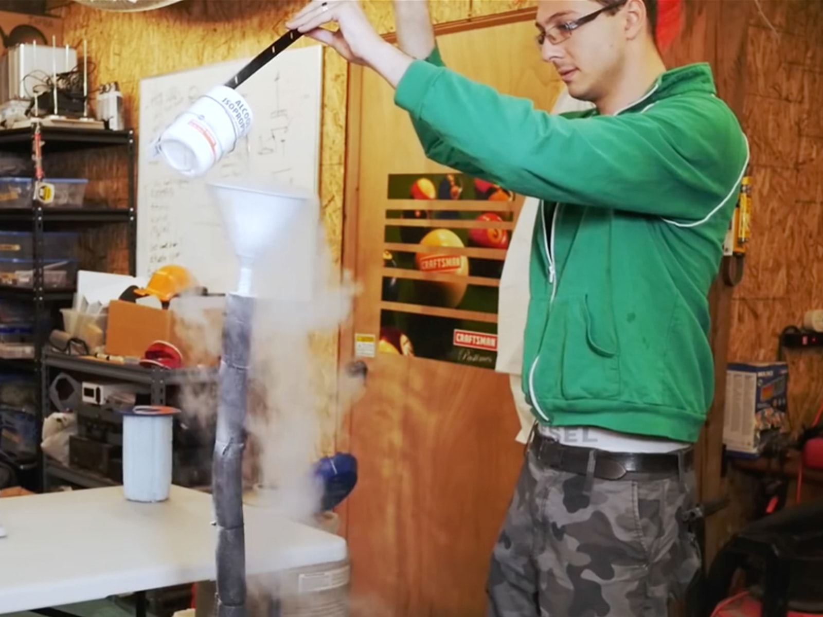 DigiPen RTIS alumus Mikhail Davidov in a lab pouring isopropyl alcohol into a steaming funnel mounted on a pipe