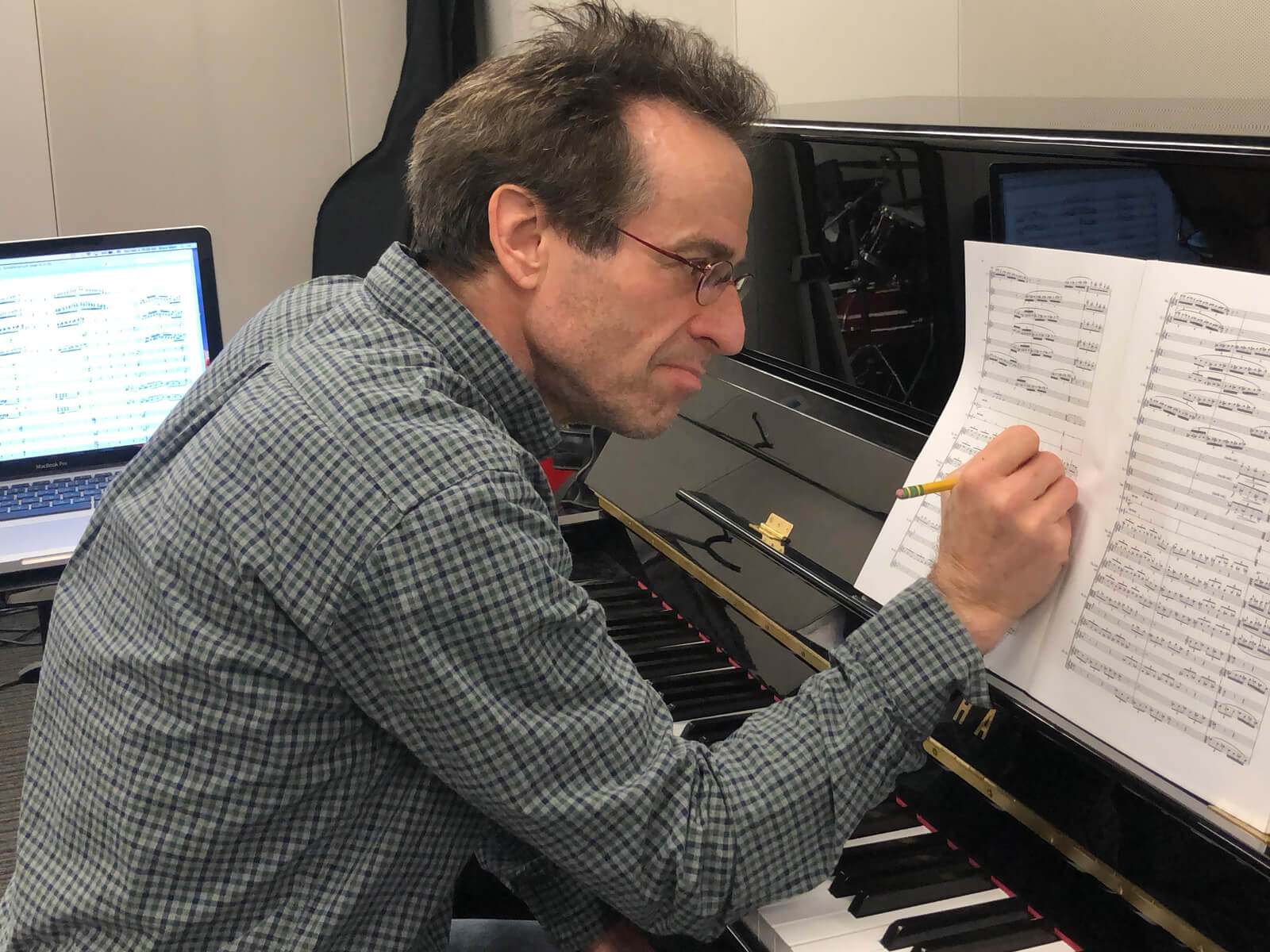 DigiPen music department chair Bruce Stark sitting at a piano, making notations on sheet music