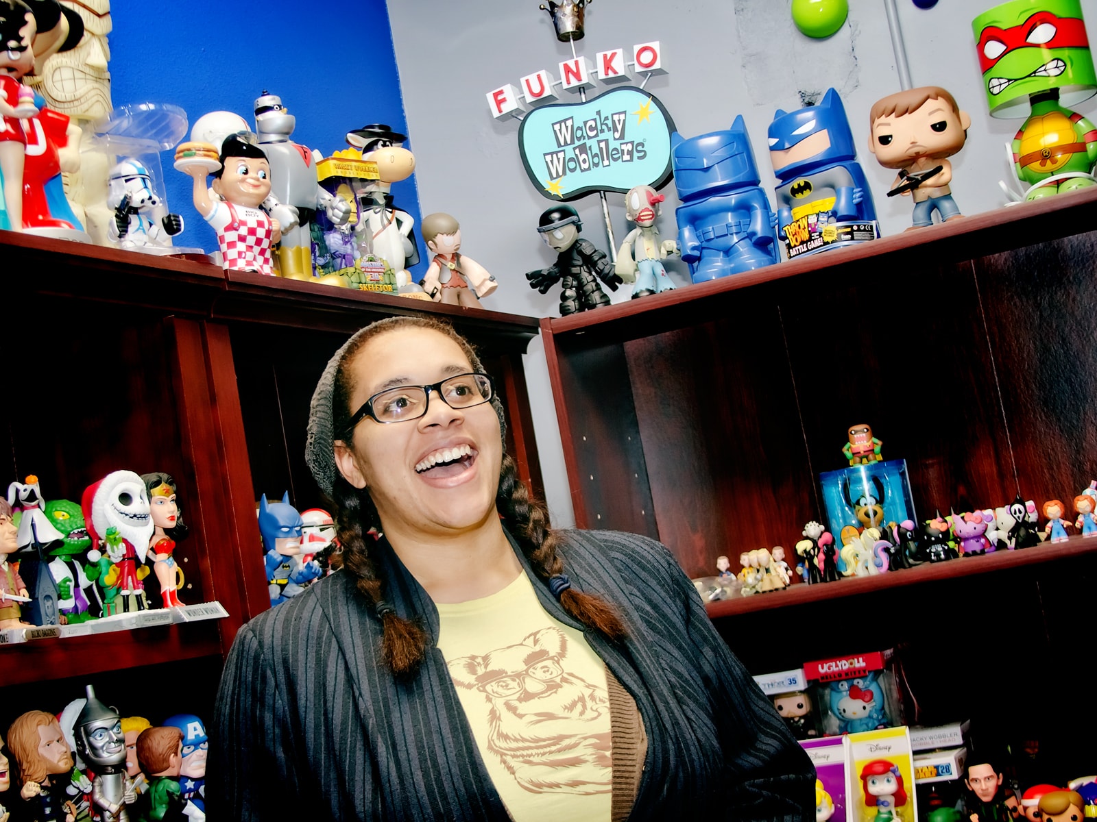 DigiPen BFA alumna Nnenna Ijiomah smiling in front of bookshelves filled with Funko figurines at the Funko office