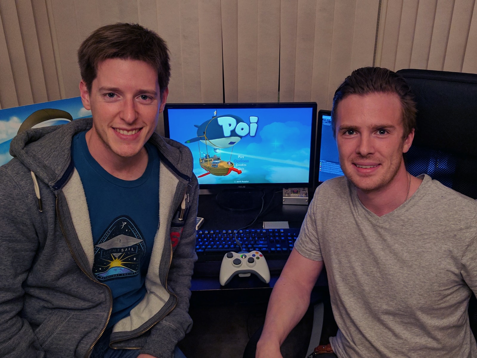 DigiPen alumni Paul Ewers and Ben Gable on launch day, smiling in front of computer monitors displaying Poi's title screen