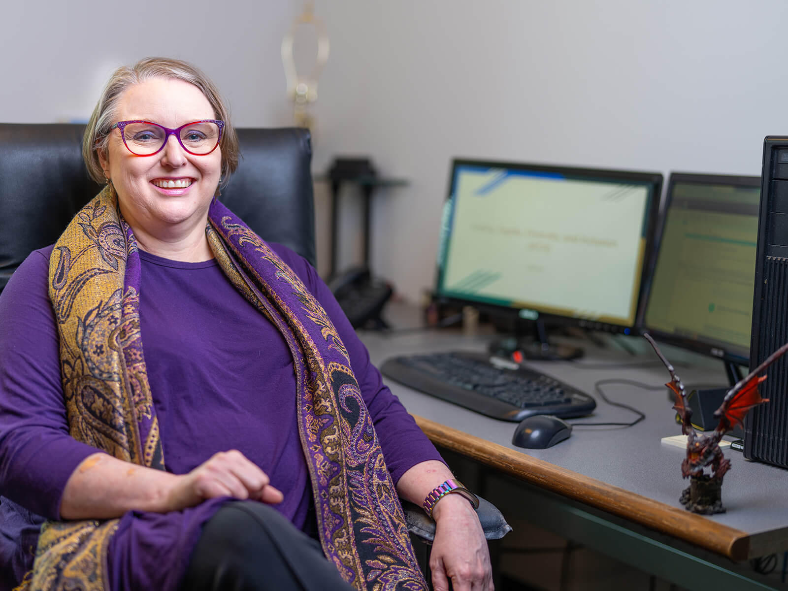 DigiPen senior lecturer Sonia Michaels sits at her desk near a dragon figurine. 