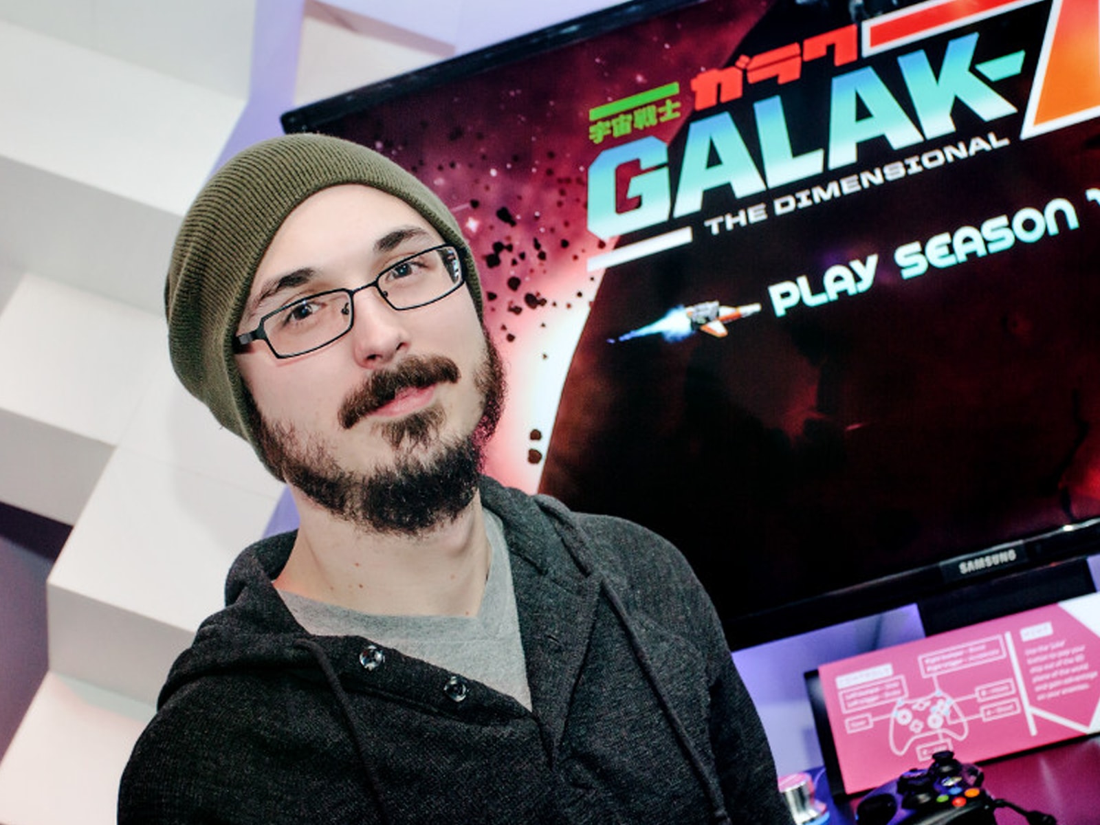 DigiPen alumnus Zach Aikman posing in front of monitor showing Galak-Z title screen at PAX2013