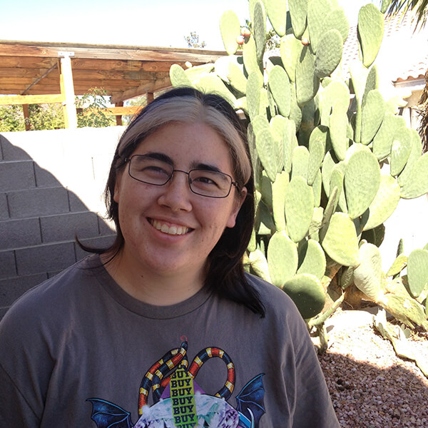 DigiPen graduate and Spry Fox senior software engineer Molly Jameson poses in front of a cactus. 