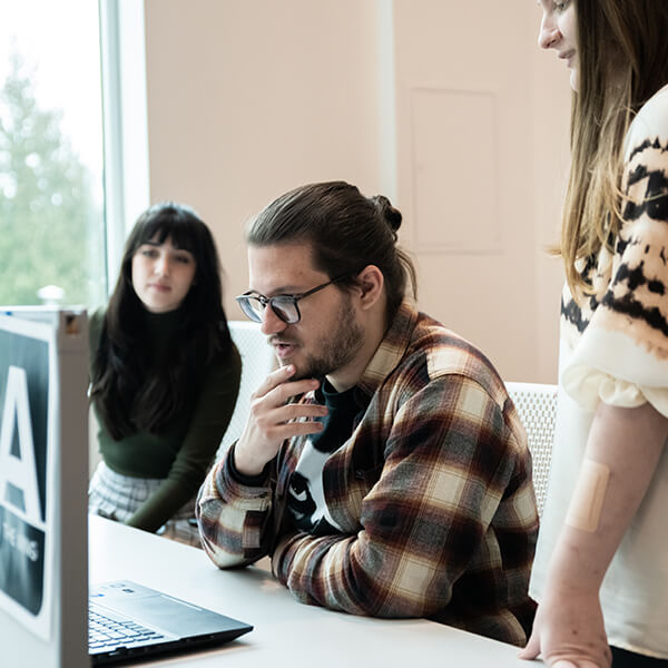 Mike Doeren looks at his laptop in DigiPen’s campus lab, surrounded by two other students.