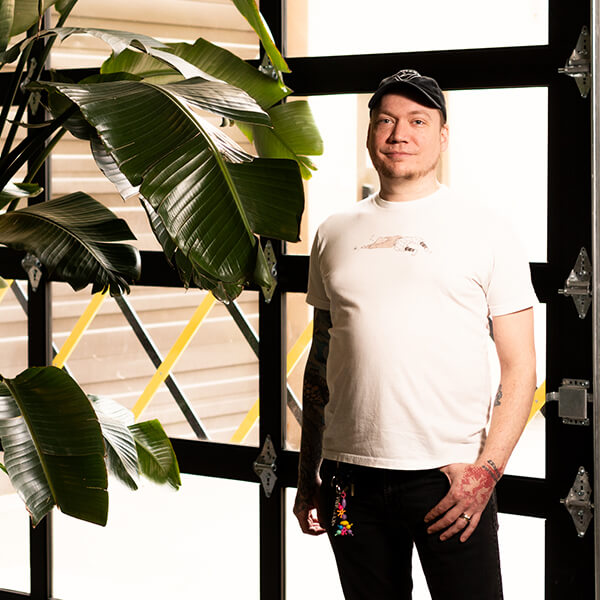 Pat Jandro poses next to a large potted plant in front of a bay door. 