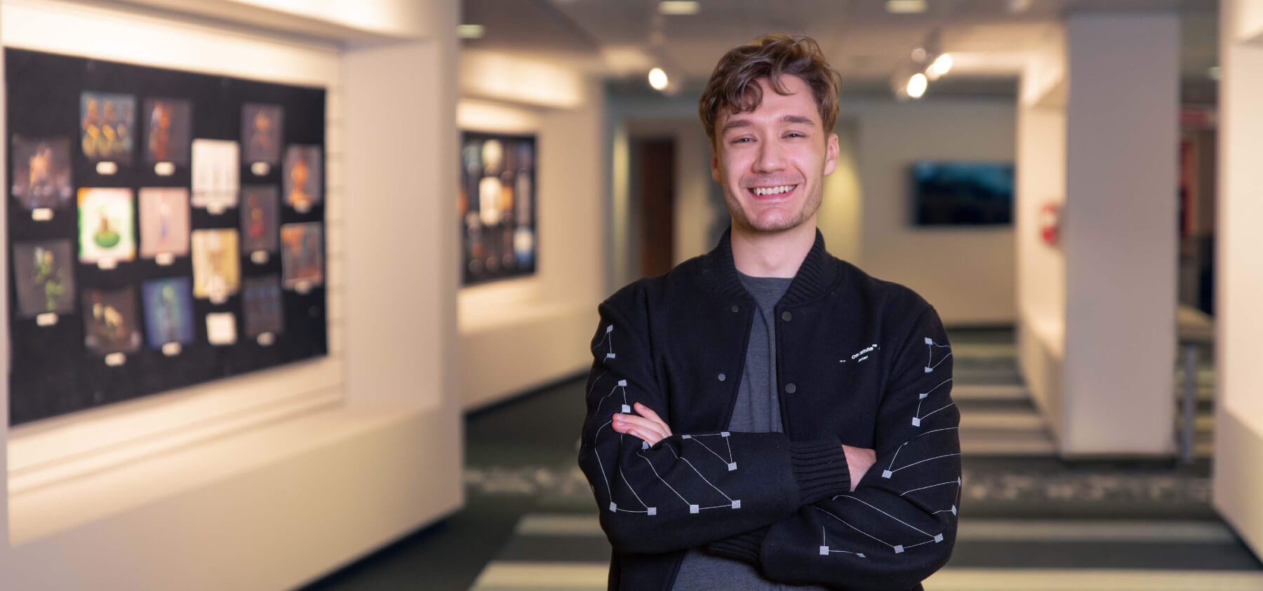 Christophe Bouchard standing in hallway with student art on walls