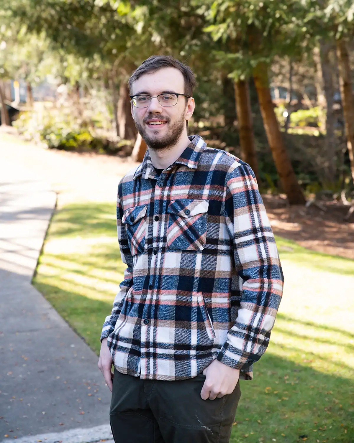 Caleb Klomparens smiles standing in front of trees
on DigiPen’s campus.