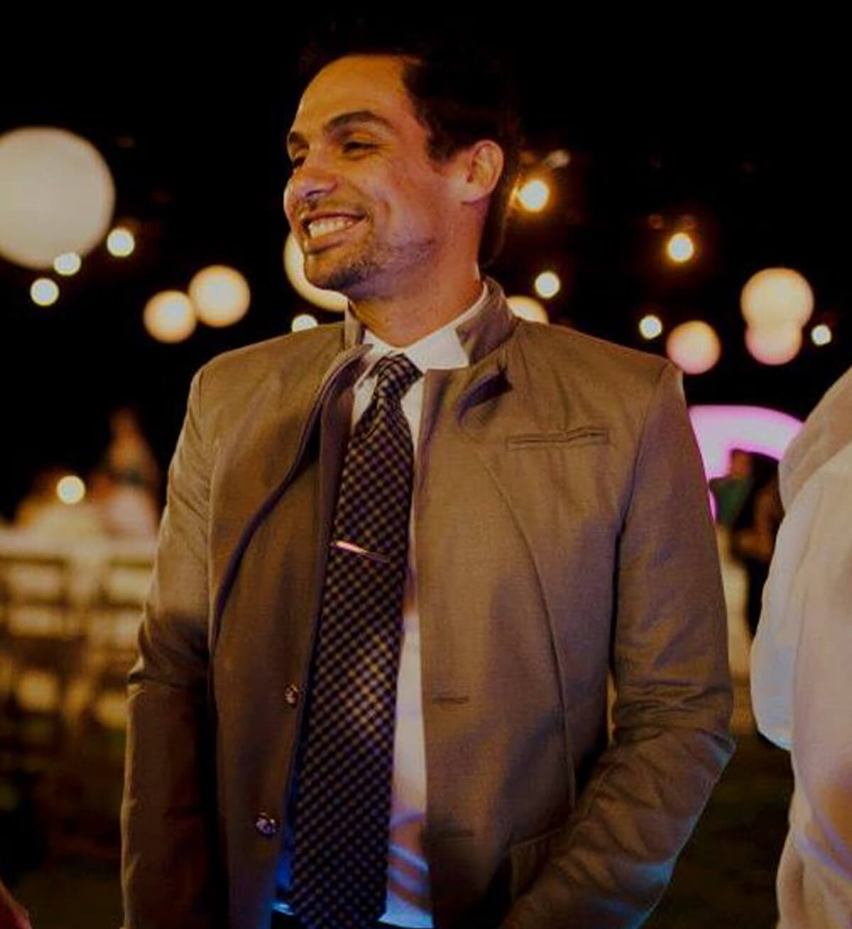 DigiPen grad Adrian Sotelo smiles in a tan suit and tie.