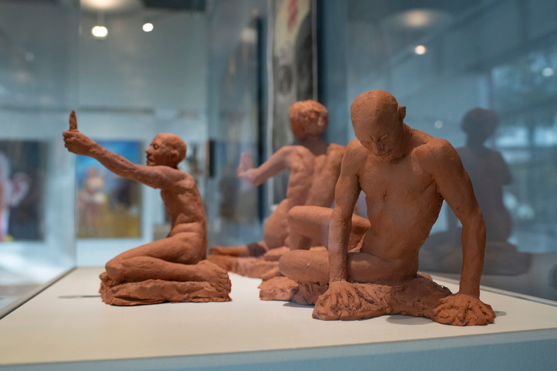 Three terracotta figure sculptures on display at museum art exhibit.